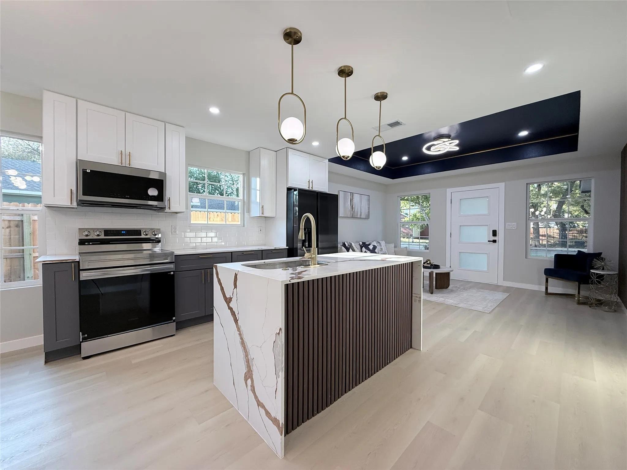 Kitchen featuring a waterfall island with stone countertop, stainless steel appliances, and two-tone cabinetry