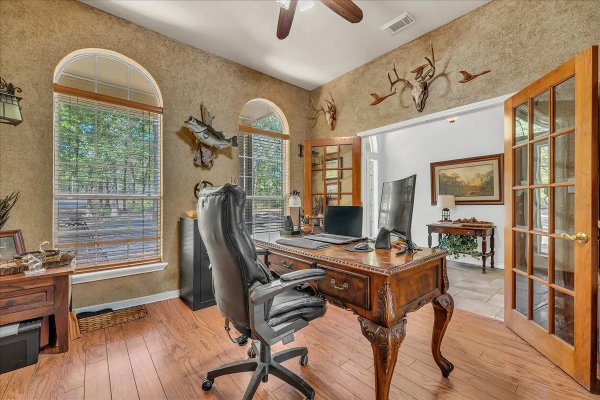Wood-finish flooring with a ceiling fan and textured wall finish
