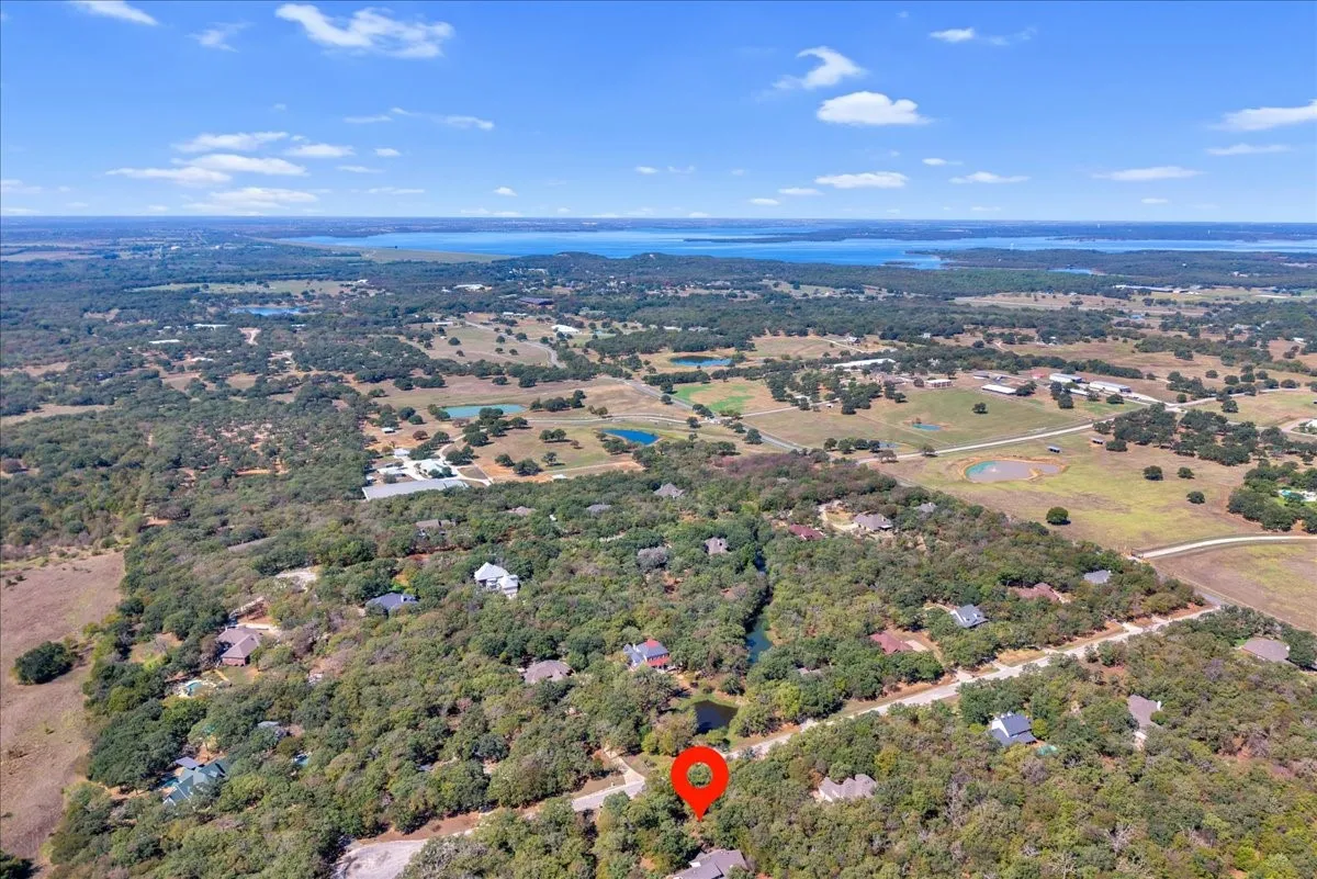 Expansive acreage with mature tree coverage, a prominent body of water in the distance, and surrounding natural landscapes