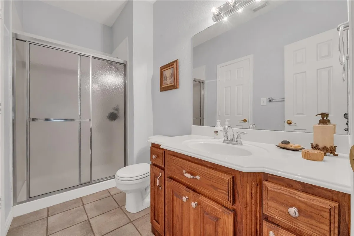 Spacious vanity with a white countertop, wood-finish cabinetry, and a single basin sink