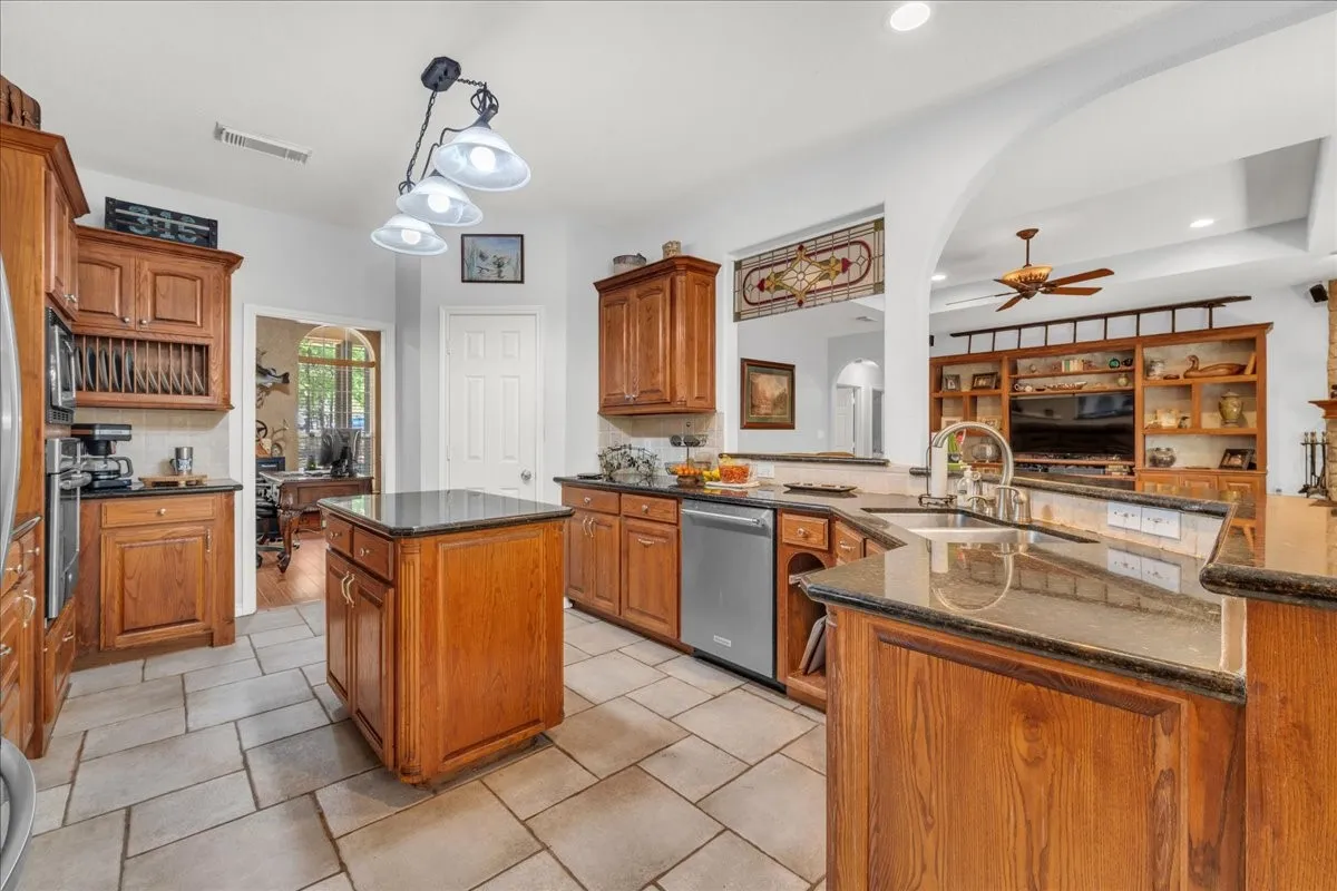 Kitchen featuring wood cabinetry, stone-look countertops, stainless steel appliances, and a central island
