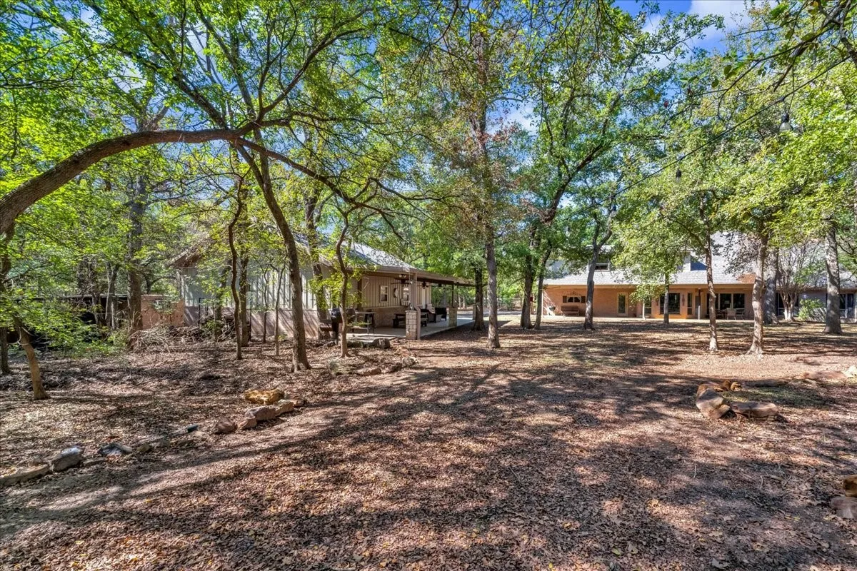 Expansive wooded grounds featuring mature trees and a secondary structure with a covered porch