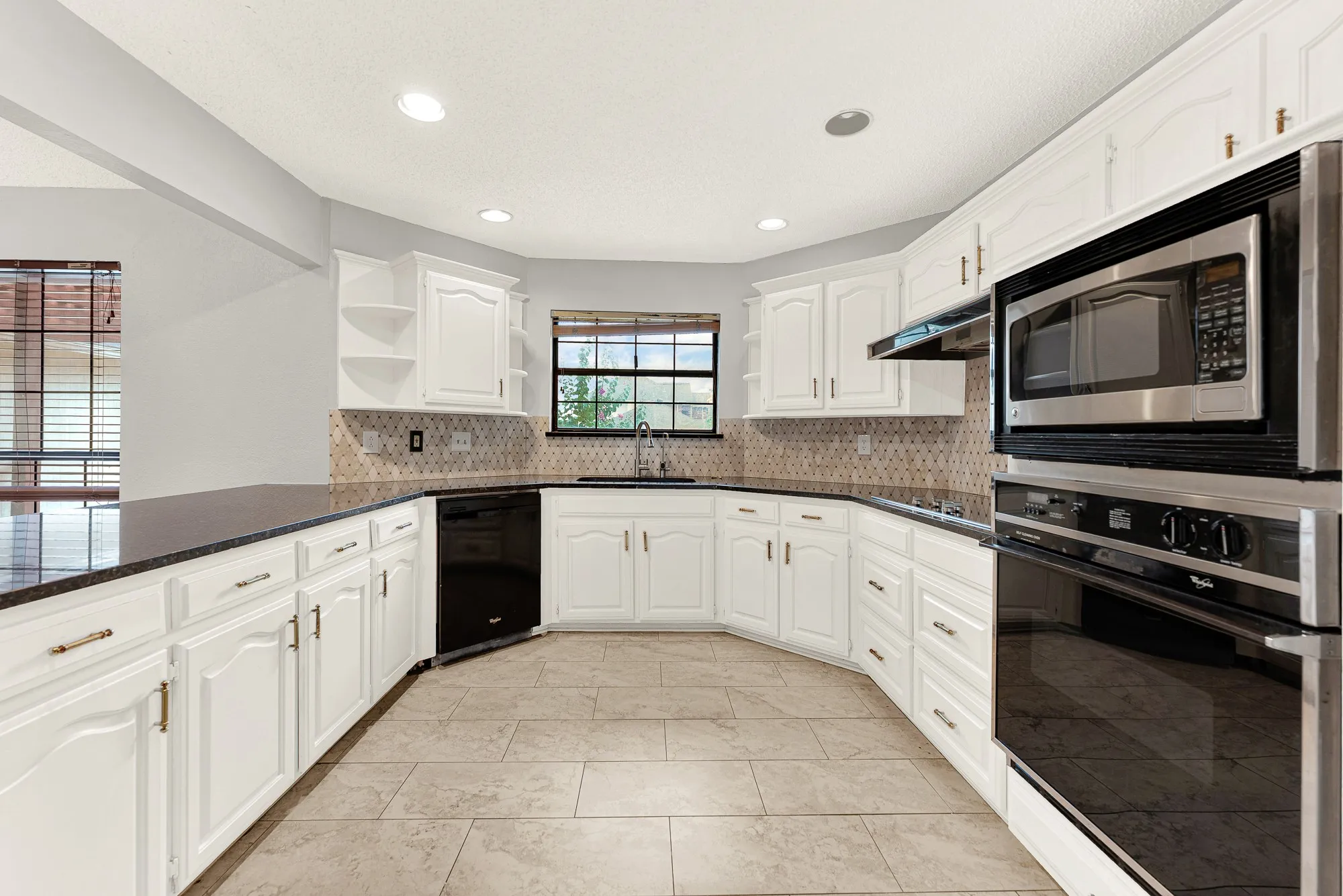 A patterned tile backsplash wraps seamlessly behind crisp white cabinetry, balancing texture with a clean, airy feel. Picture baking holiday treats while warm aromas fill every corner of this inviting layout.