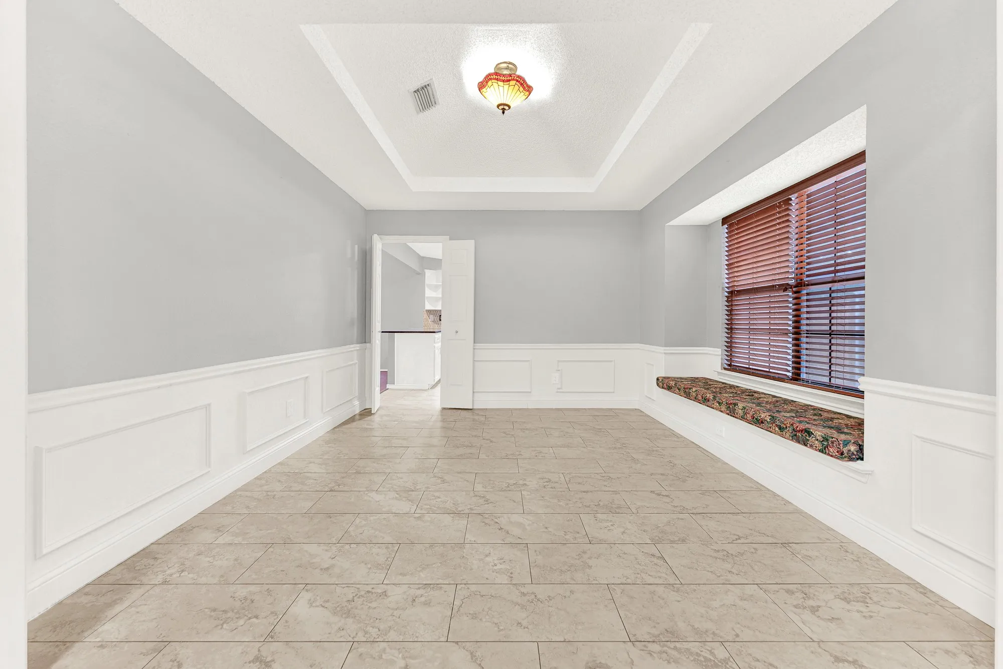 An elegant recessed tray ceiling draws the eye upward, catching soft glow from the central light fixture. Picture hosting intimate dinner parties where warm conversations linger long after dessert is served