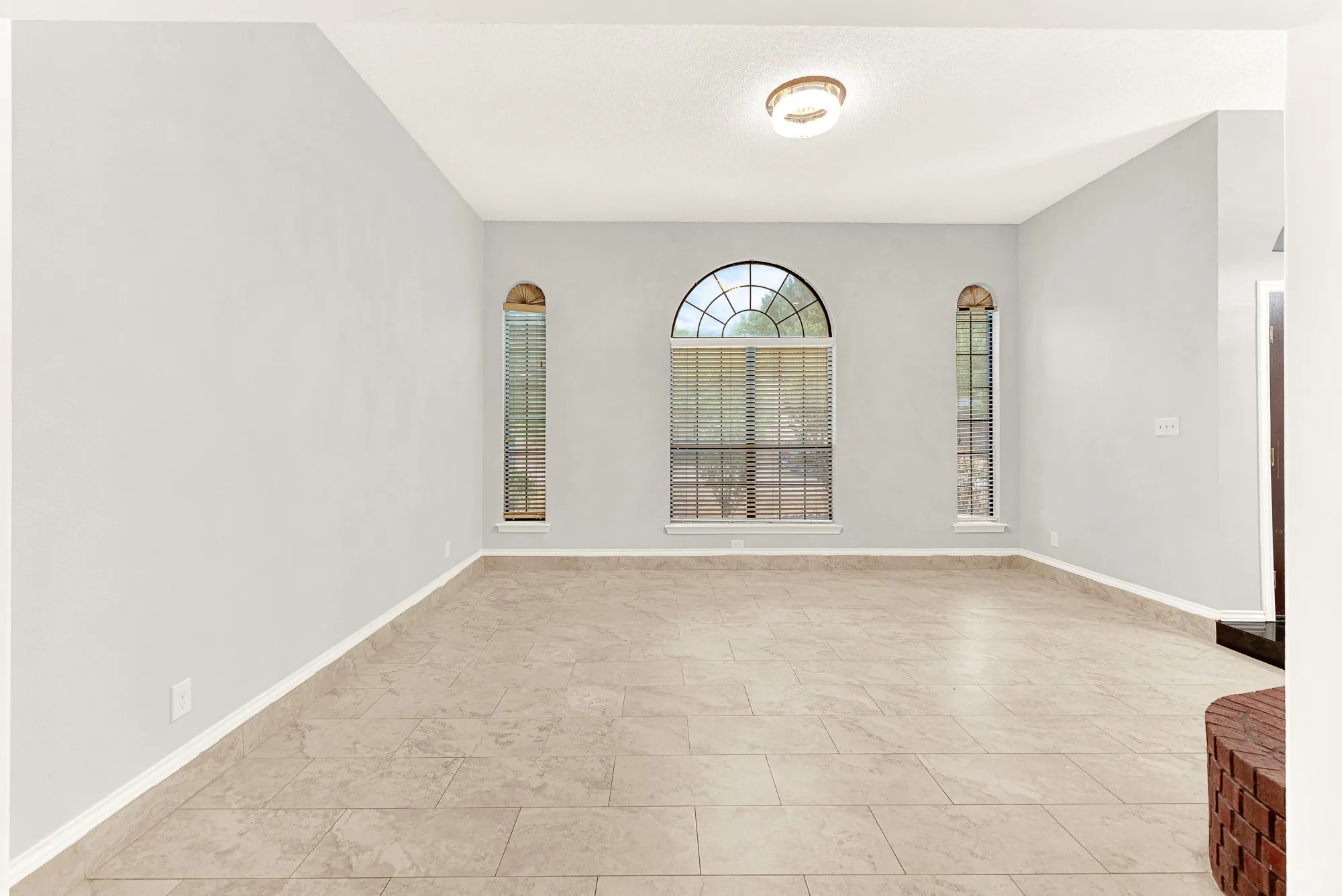 Symmetrical arched windows frame the back wall, creating a serene focal point that draws your eyes outward. Unwind here after a long day, watching the evening shadows softly lengthen across the quiet room