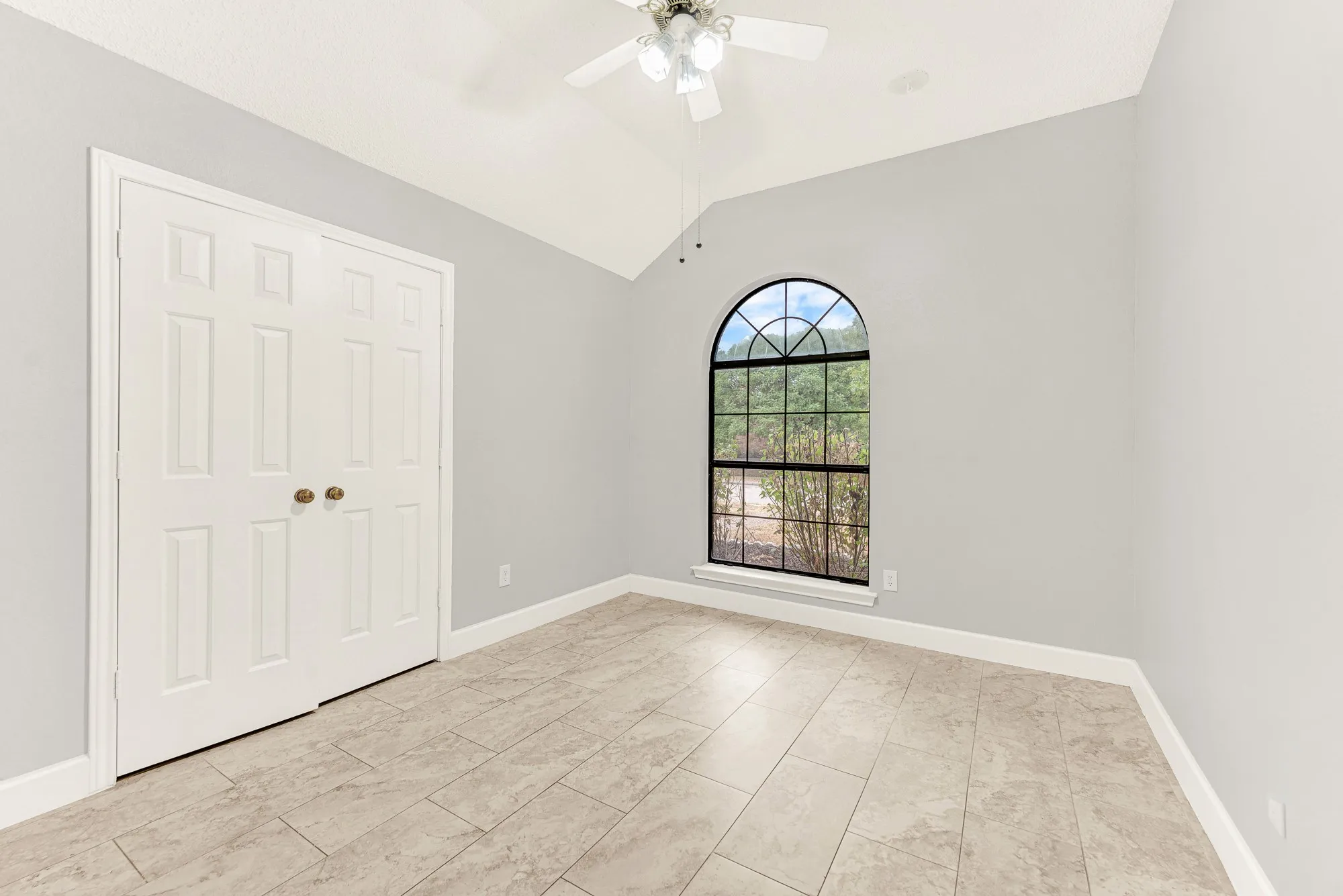 A grand arched window serves as a striking centerpiece, pouring natural daylight across the clean tiled floor. Imagine welcoming out-of-town loved ones into a bright, restful sanctuary where they can easily unpack and settle in