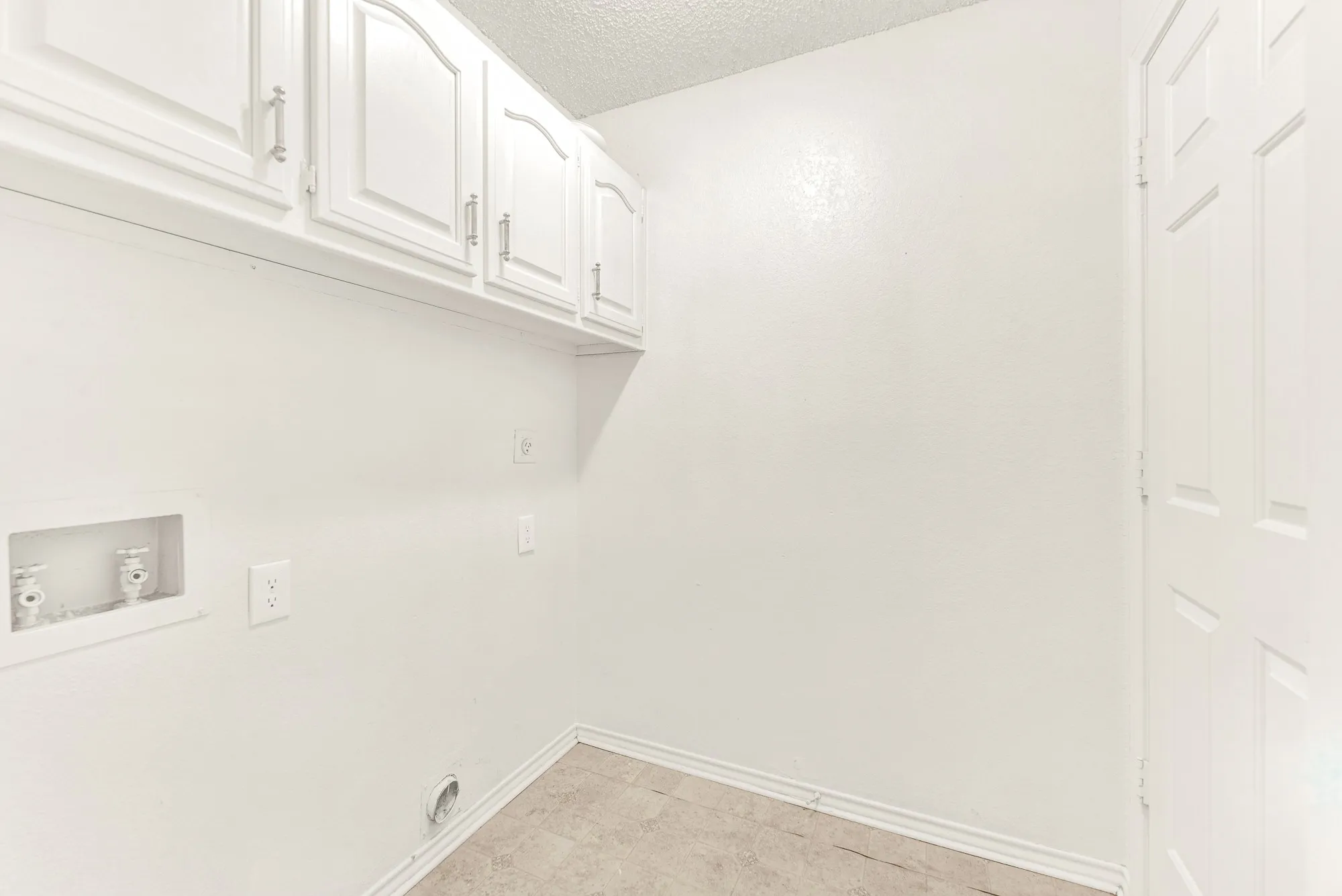 Upper white cabinetry maximizes vertical space, providing clean and concealed storage overhead. Visualize breeze-through laundry routines made effortlessly organized in this functional, clutter-free utility hub.