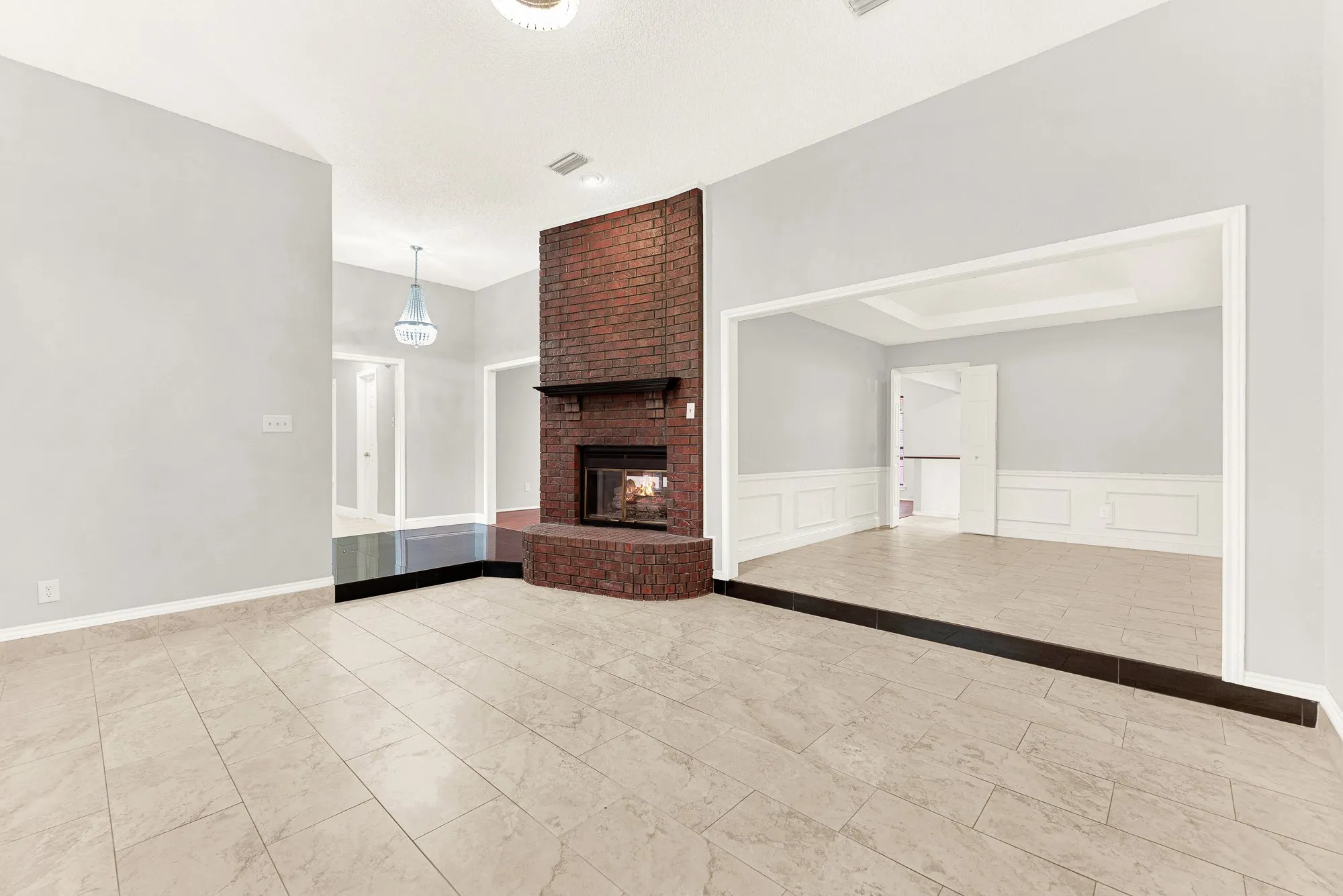 A floor-to-ceiling brick fireplace serves as a grounding centerpiece, anchoring the open layout. Imagine hosting cozy game nights with friends curled up around a crackling hearth.
