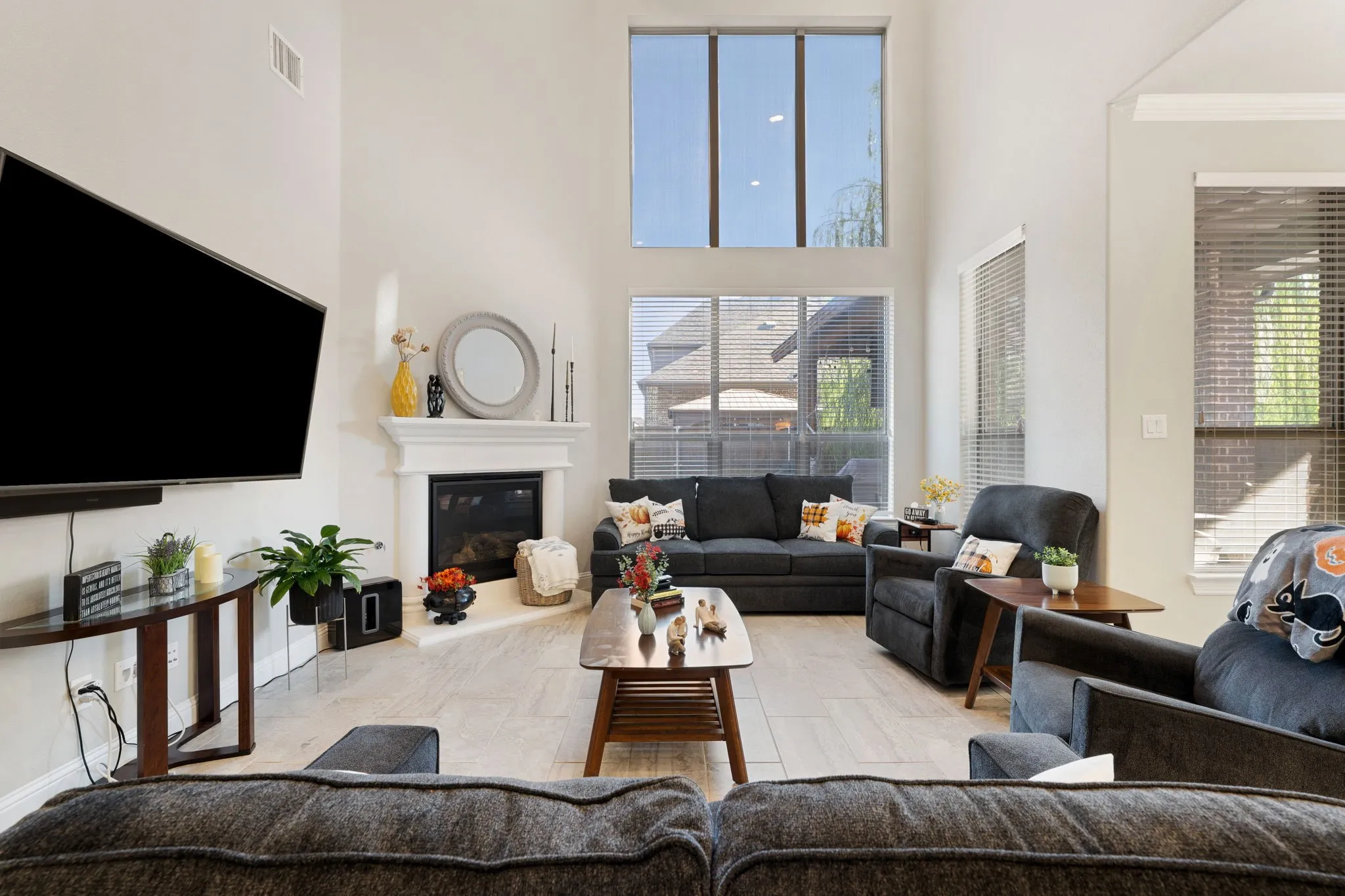 Living area featuring a floor-to-ceiling fireplace with a mantel, soaring ceilings, and a combination of large windows and transom windows