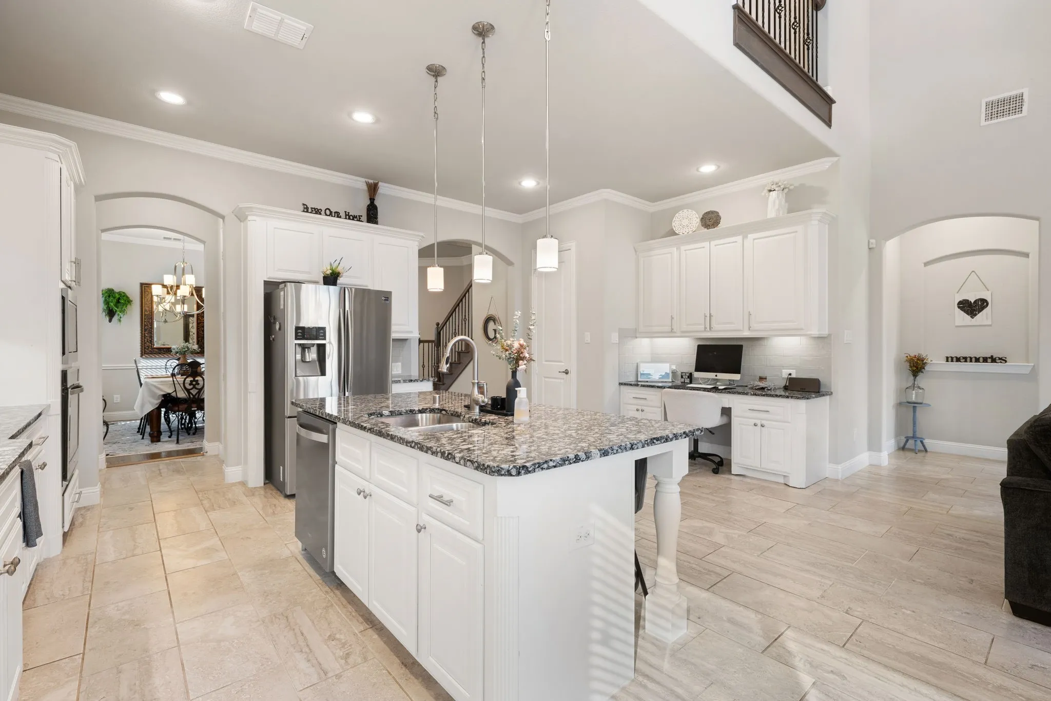 Kitchen featuring a large central island with granite countertop, white cabinetry, and stainless steel appliances