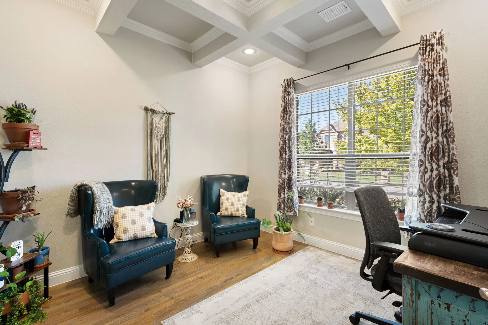 Coffered ceiling with recessed lighting, large window with blinds and patterned curtains, light-toned walls, and wood-finish flooring