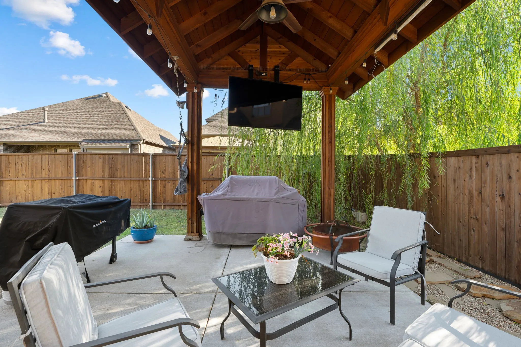 Expansive concrete patio featuring a wood pergola with ceiling fan and integrated lighting