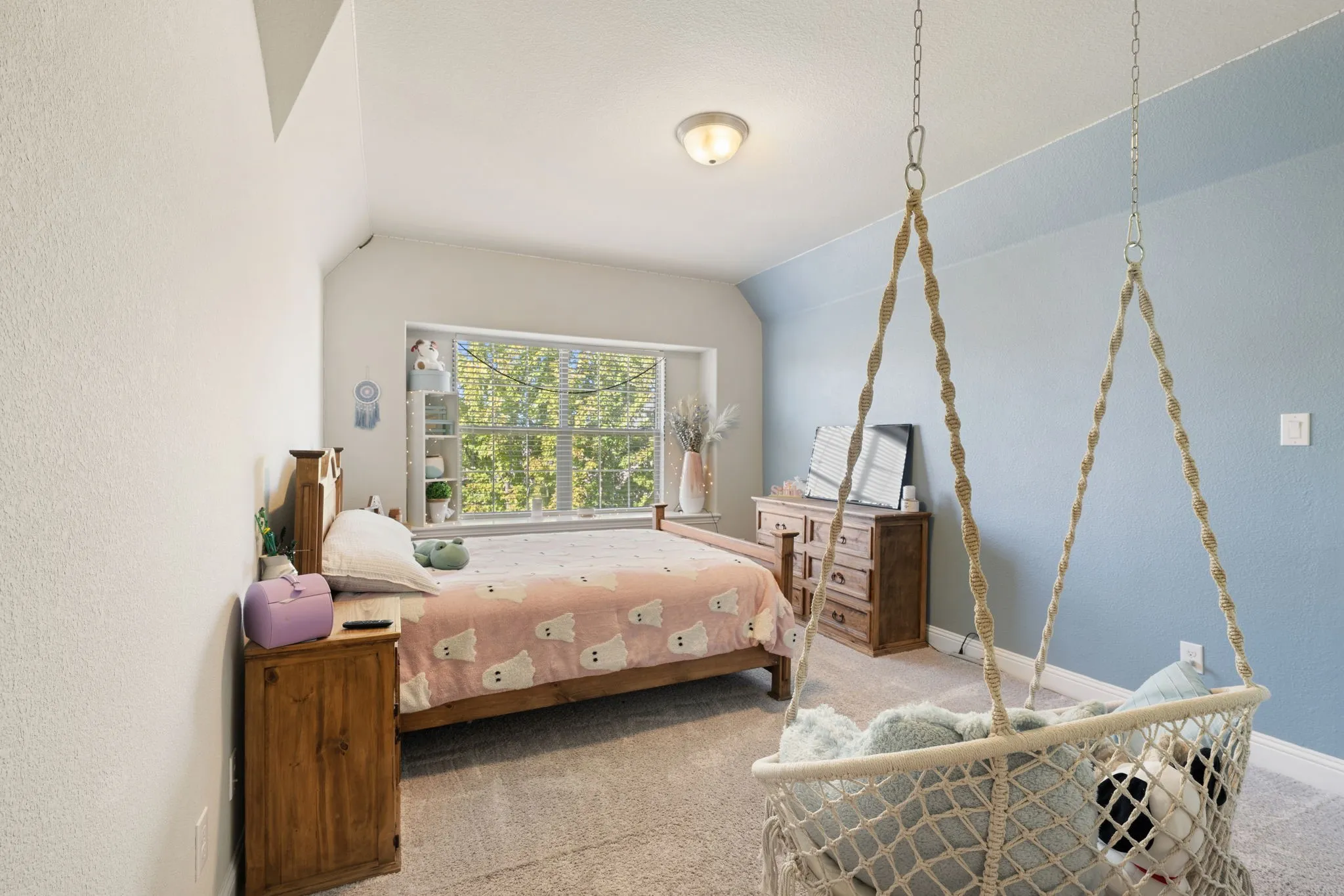 Bright interior with sloped ceilings and a window featuring horizontal blinds