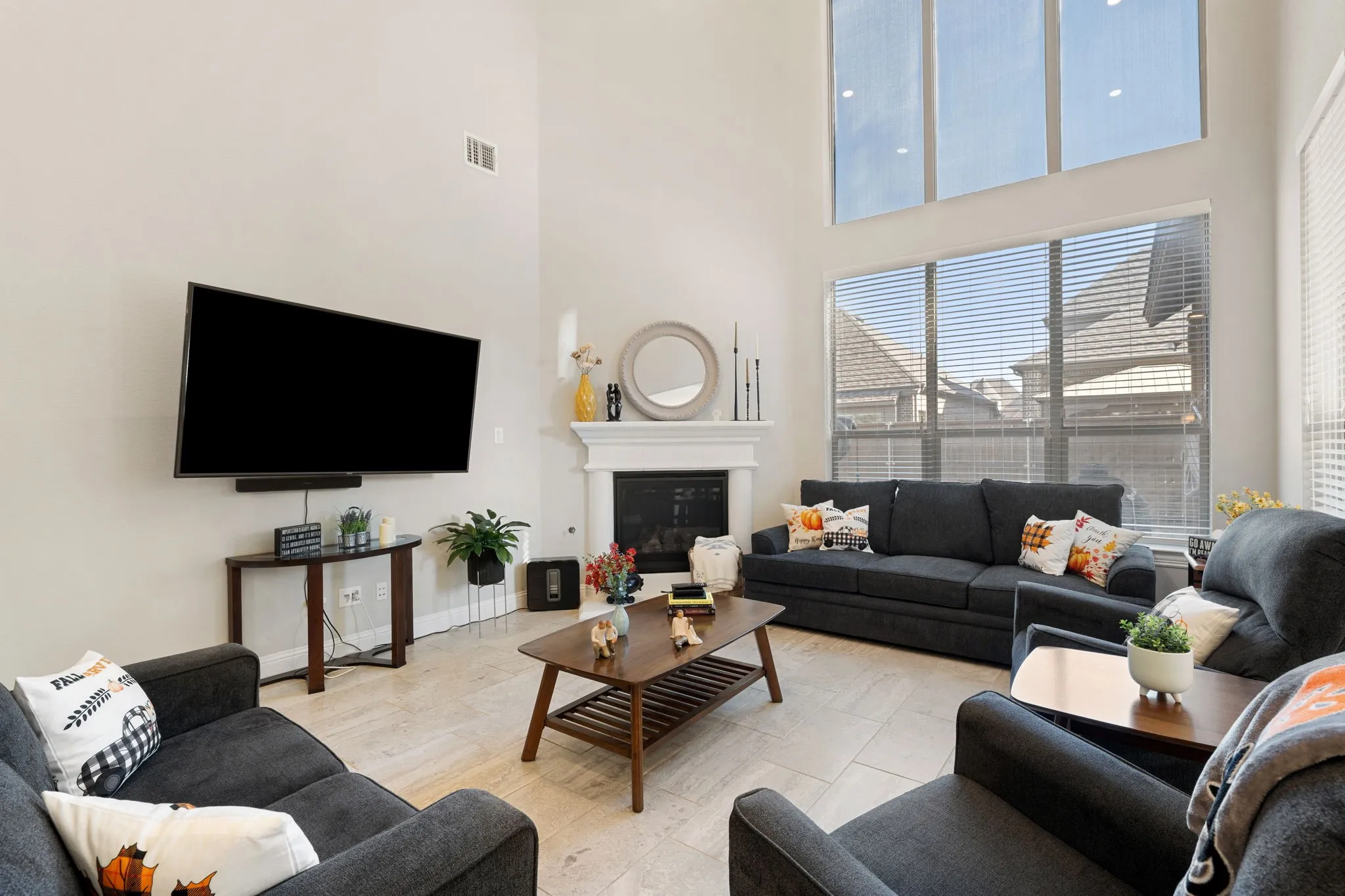 Living area featuring a floor-to-ceiling fireplace with a white mantel, expansive windows, high ceilings, and tiled flooring