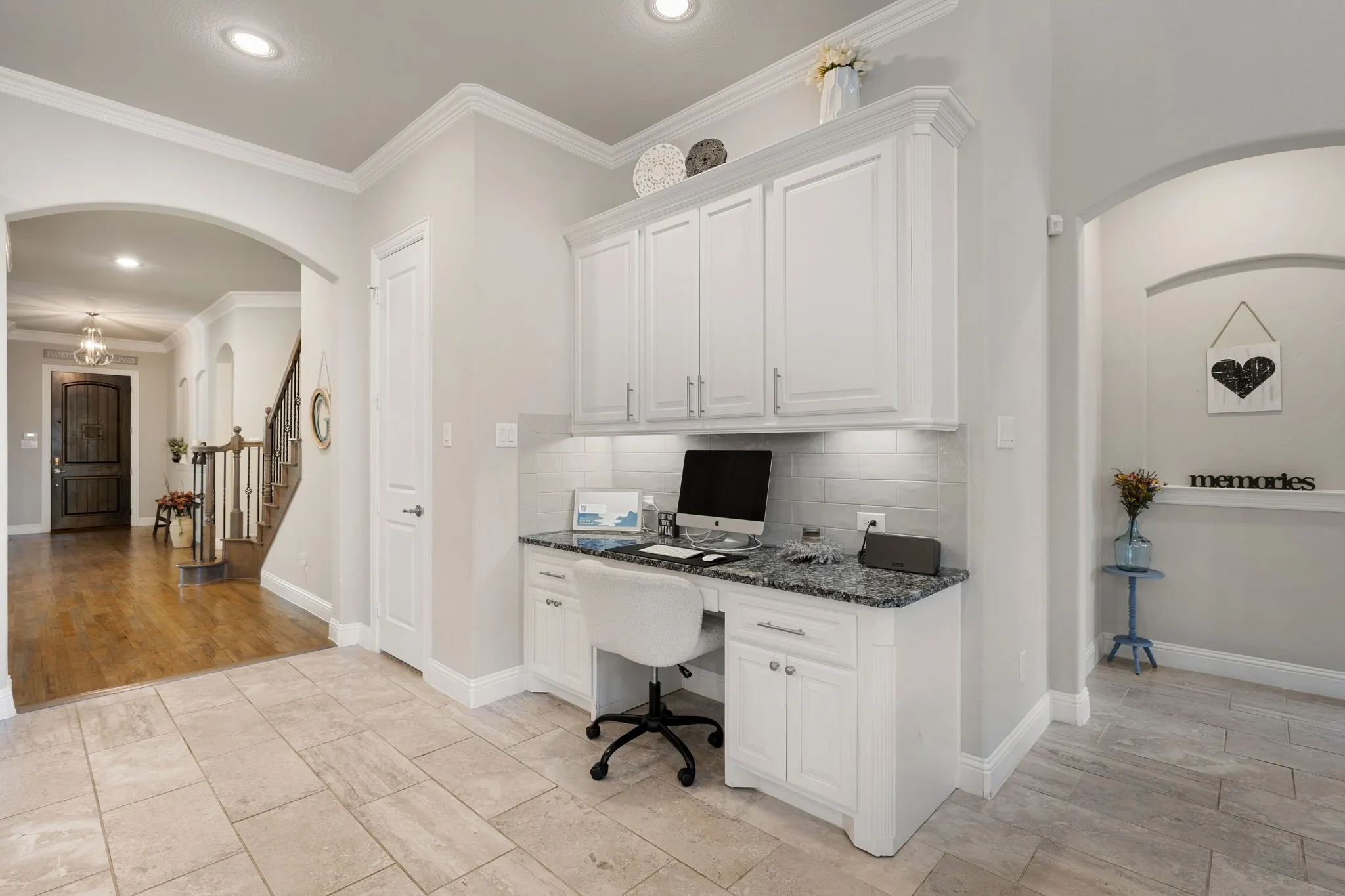 Built-in desk with white cabinetry, granite-style countertop, and subway tile backsplash