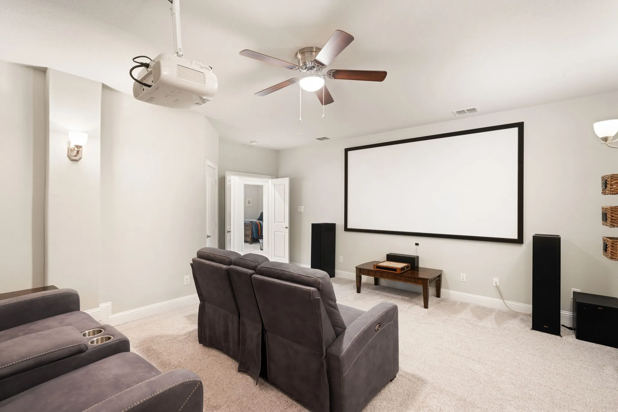 Media room featuring a ceiling-mounted projector, large projection screen, and ceiling fan with integrated lighting