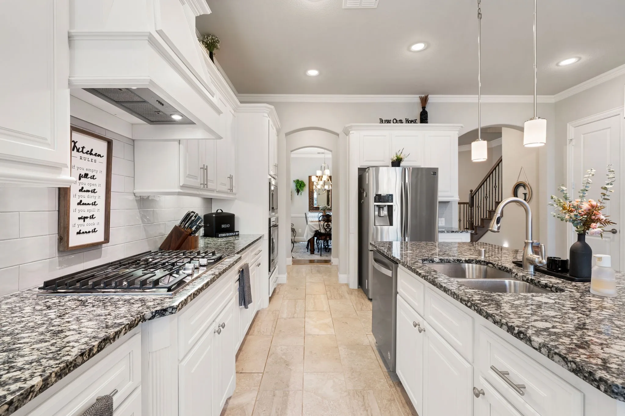 Gourmet kitchen featuring white cabinetry, granite countertops, stainless steel appliances, a gas cooktop, and a double basin sink with a gooseneck faucet
