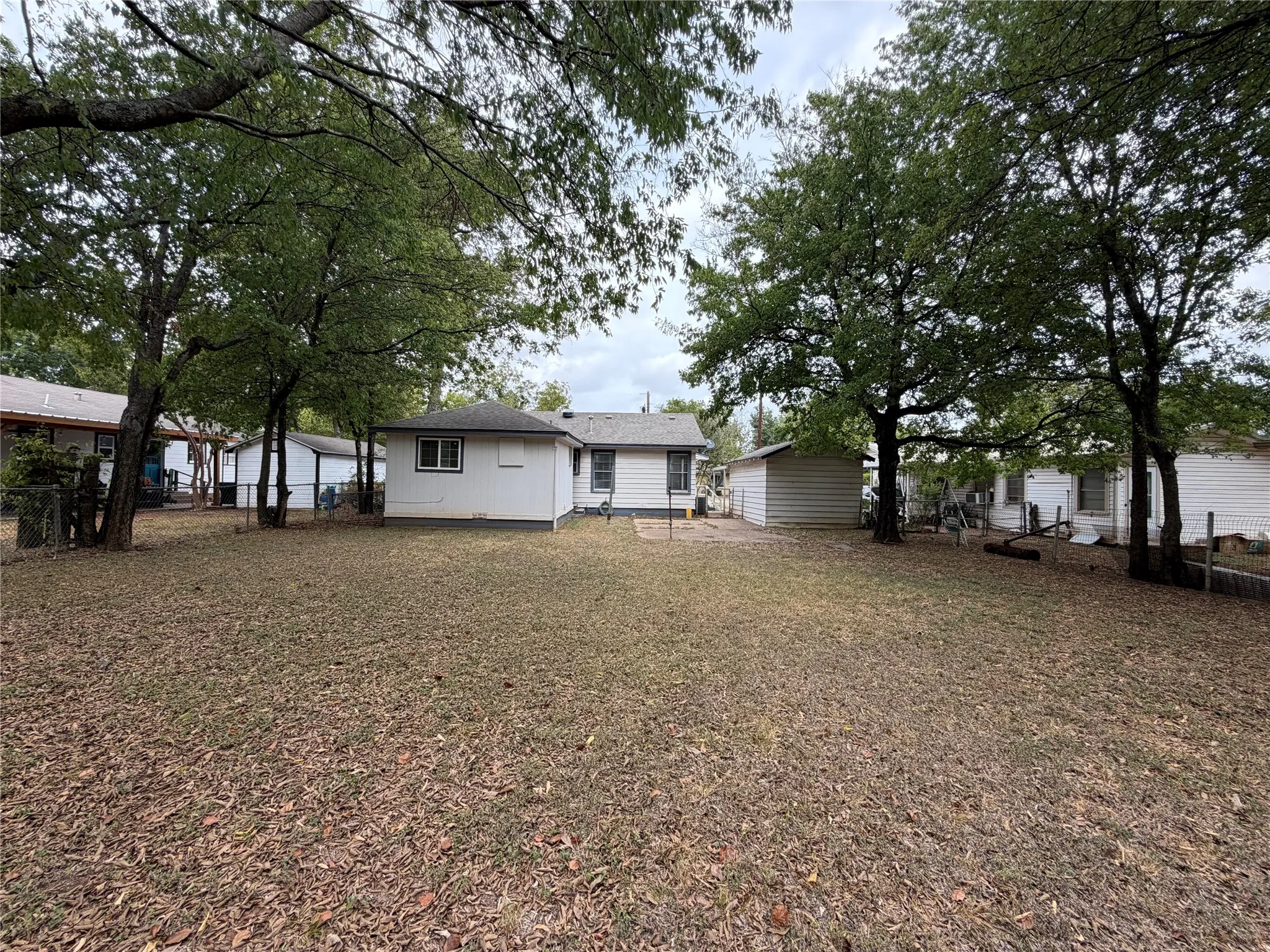 Expansive backyard with a level lawn, mature trees, and a detached storage shed