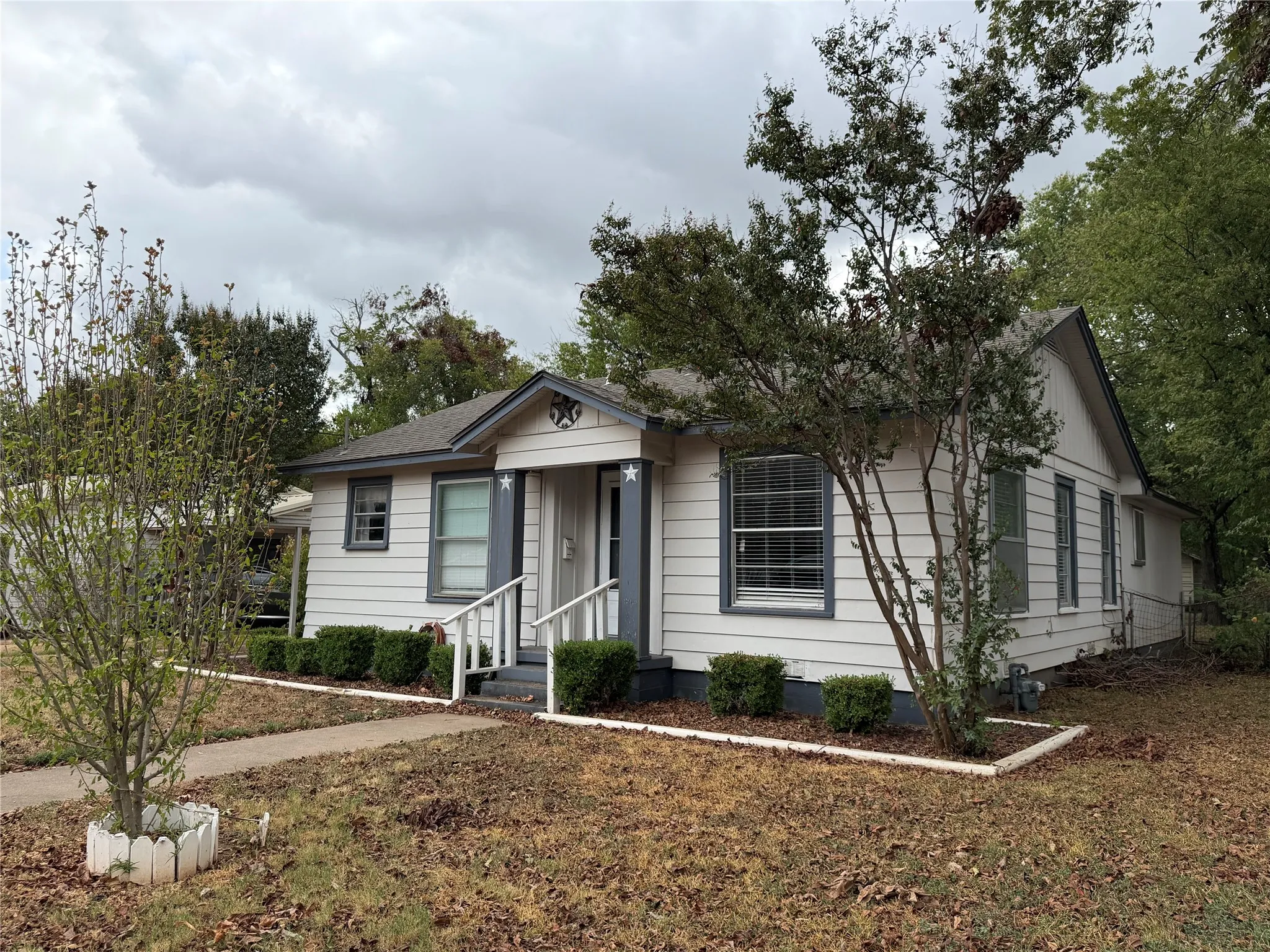White siding exterior with grey trim, covered porch entry, and a pitched roof