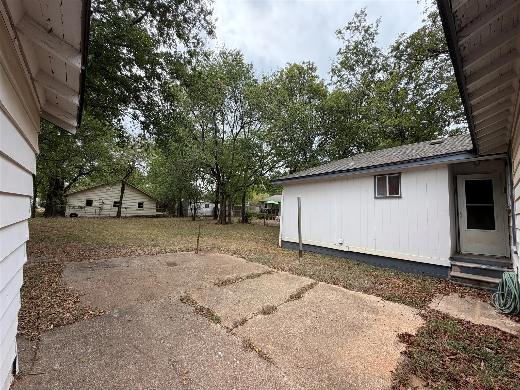 Spacious yard featuring mature trees and a concrete patio area