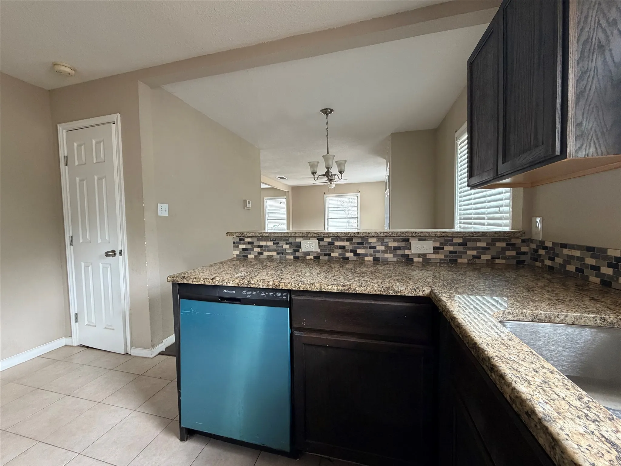 Kitchen featuring a built-in dishwasher, granite countertops, and a mosaic tile backsplash