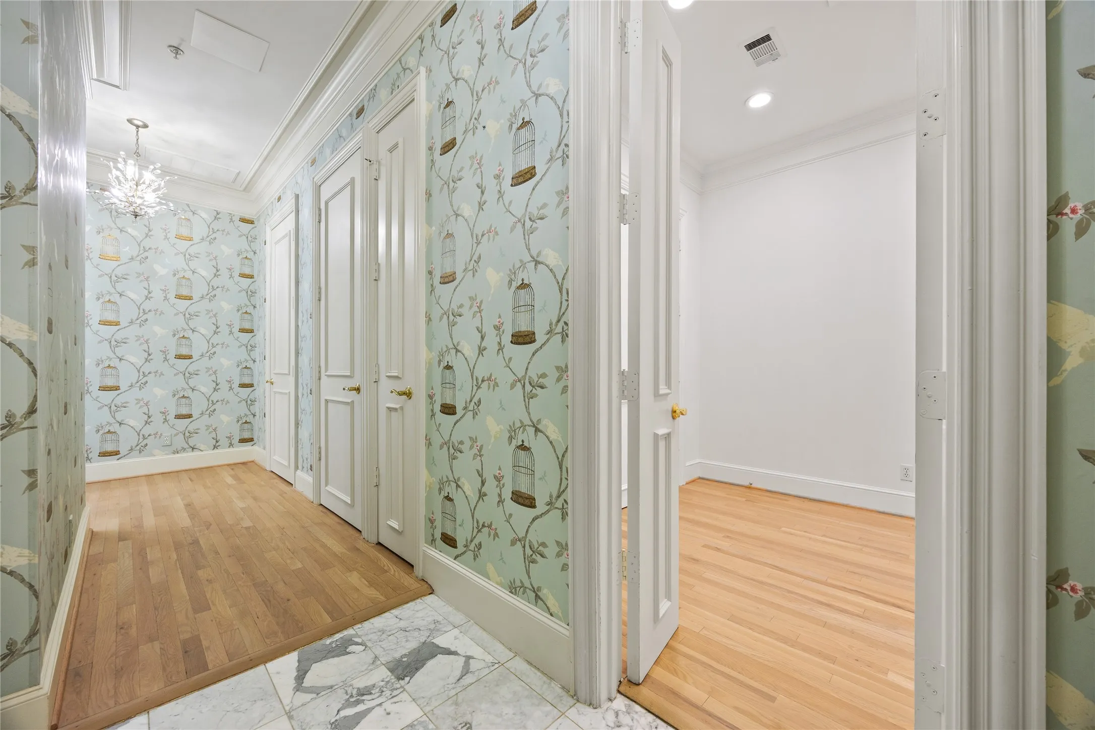 Hallway featuring decorative wallpaper, wood-finish flooring, and white paneled doors