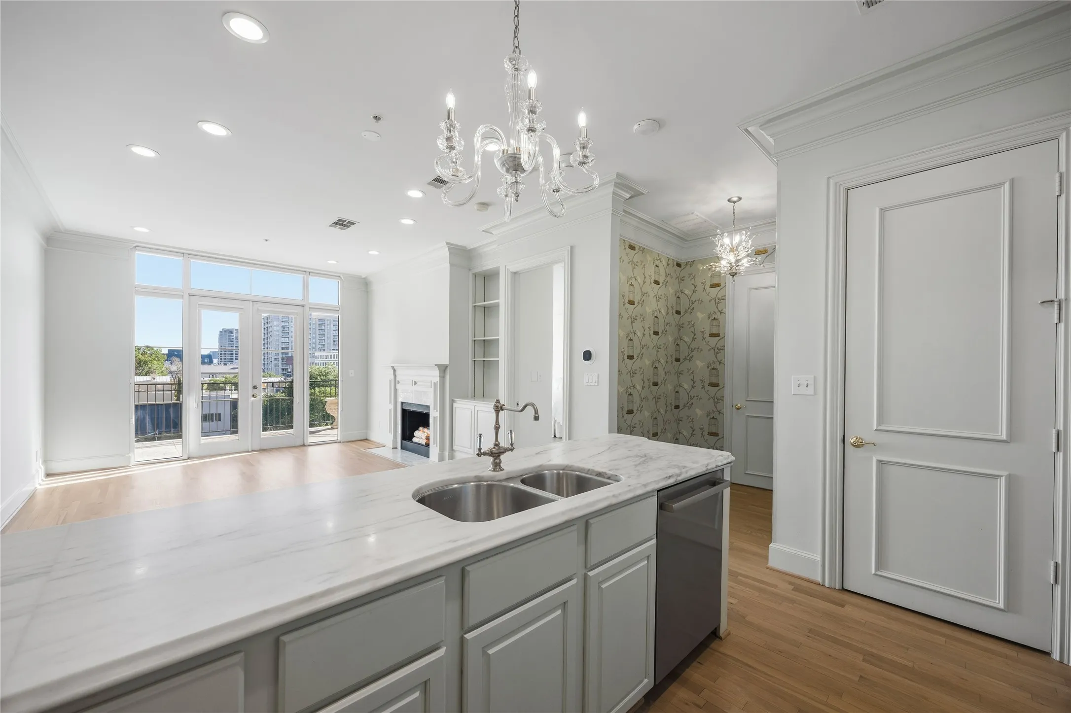 Open-concept kitchen featuring white cabinetry, stainless steel appliances, and a central island with a sink