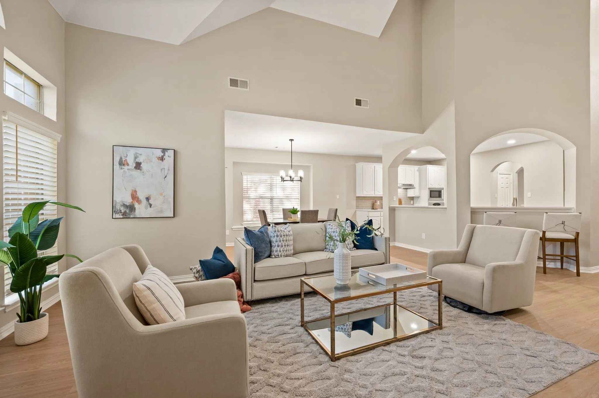 Enjoy room to gather in this light-filled living space, with tall ceilings, warm flooring & arched openings toward the kitchen.