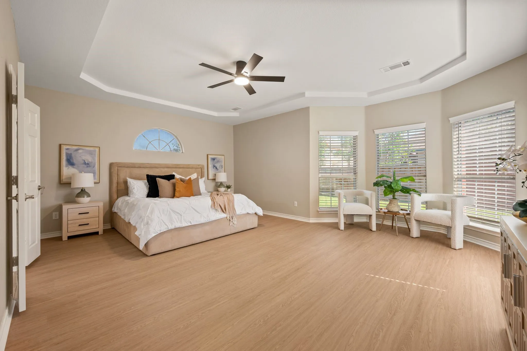 Unwind in this spacious bedroom retreat, featuring a tray ceiling, ceiling fan & a sunny bay-window sitting area.