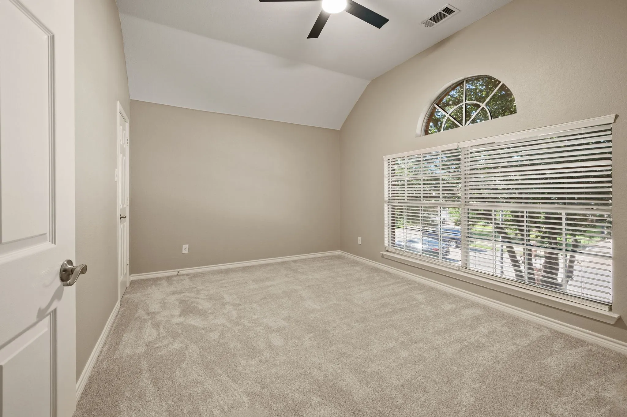 A beautiful arched window accent & vaulted ceiling give this light-filled bedroom extra charm.