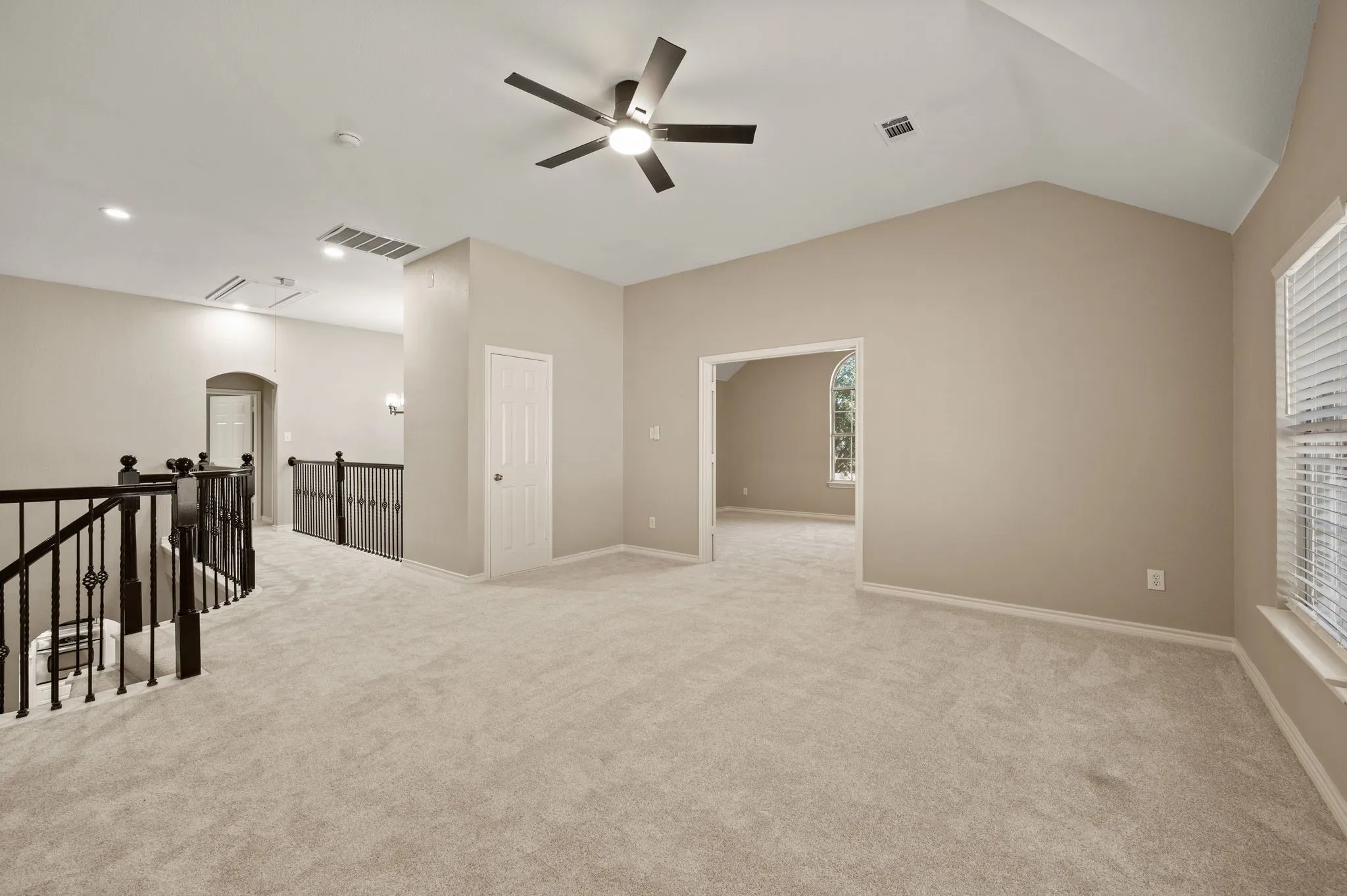 Ready for game nights or a cozy lounge, the open upstairs living area offers flexible space beside the decorative iron railing.