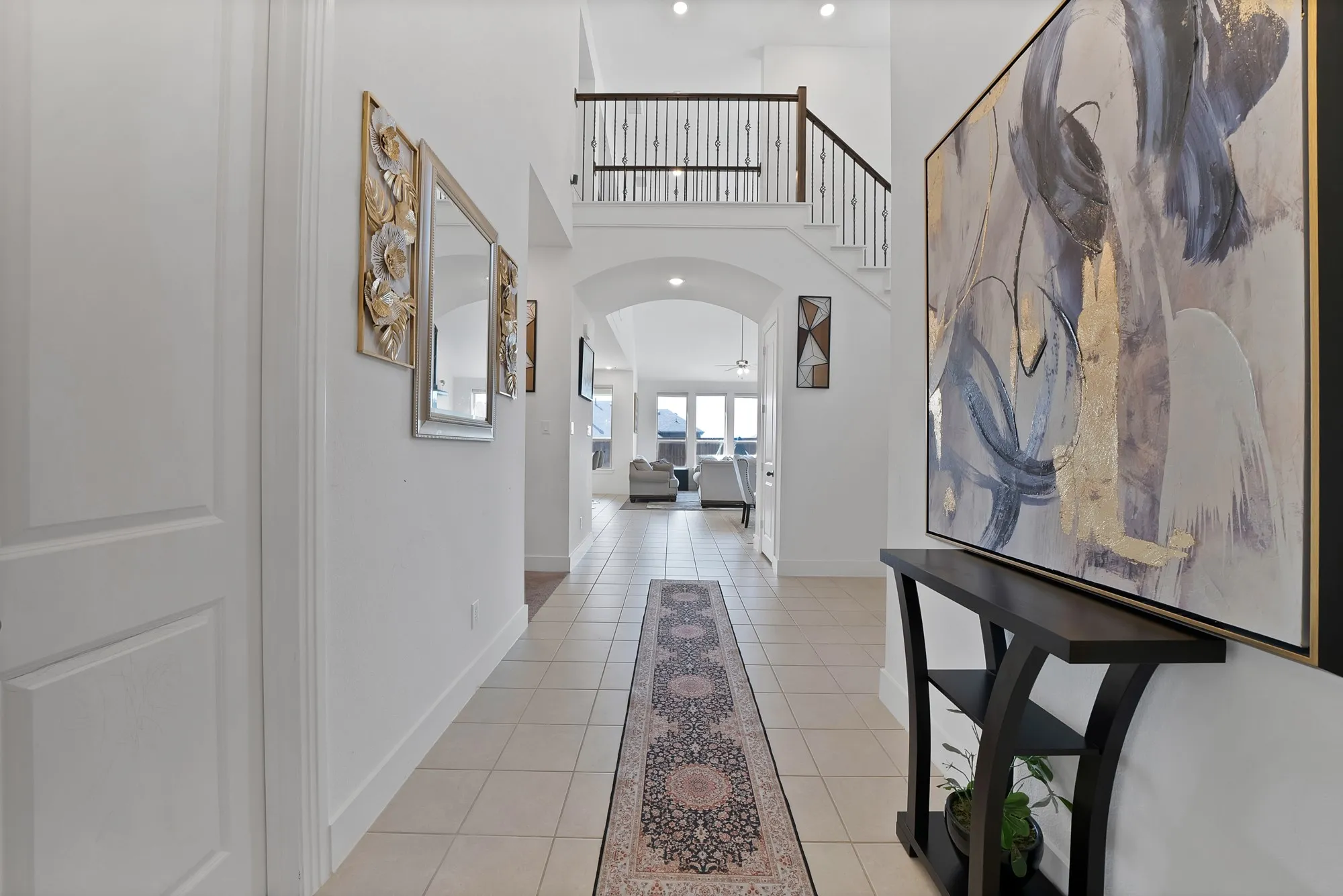 Two-story entryway featuring a tiled floor, arched doorways, and a staircase with dark wood-finish handrails and black metal balusters