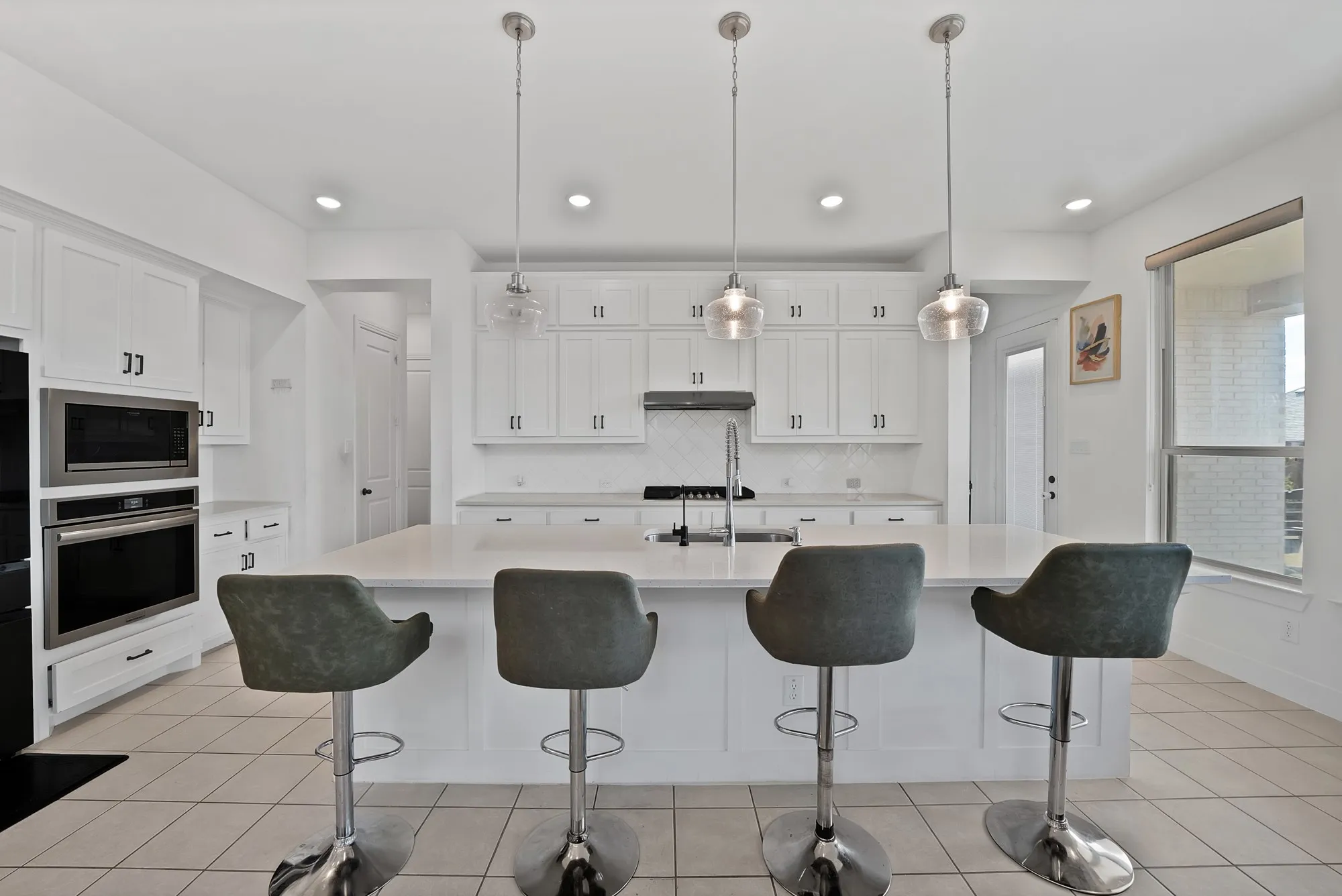 White shaker cabinetry, built-in stainless steel appliances, a large center island, and tiled flooring