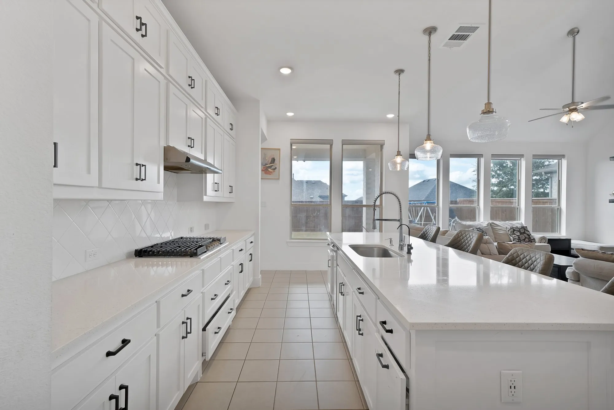White cabinetry with black hardware, white countertops, built-in gas range, tile backsplash, and recessed lighting