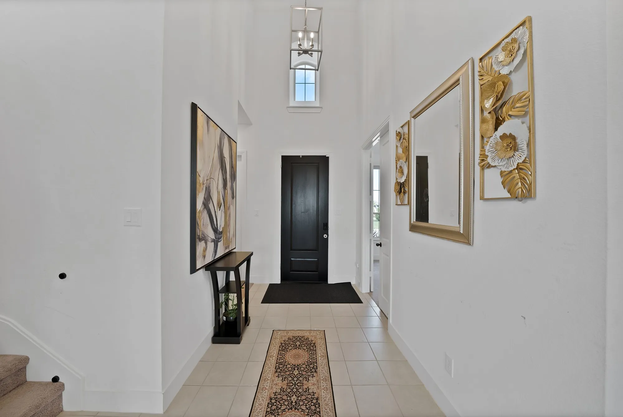 Two-story entryway featuring a black panel door, a black console table, and a contemporary pendant light fixture