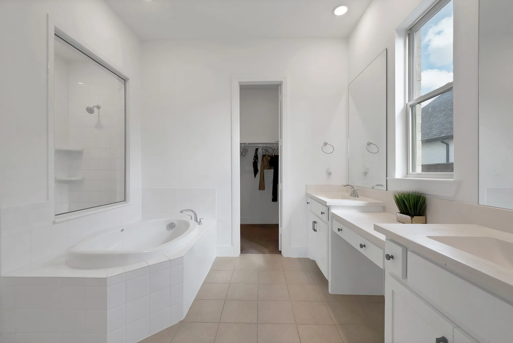 Built-in soaking tub, separate glass-enclosed shower with tile surround, dual vanity with solid surface countertops, and recessed lighting