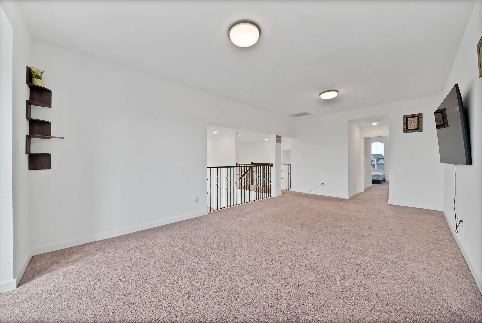 Spacious carpeted area with neutral wall tones and flush-mount lighting