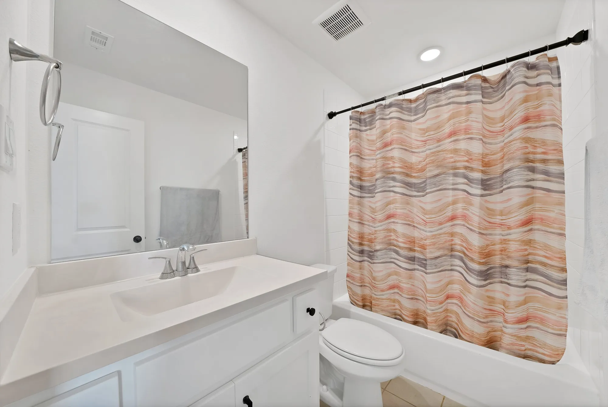 White vanity with integrated sink, chrome faucet, and expansive mirror