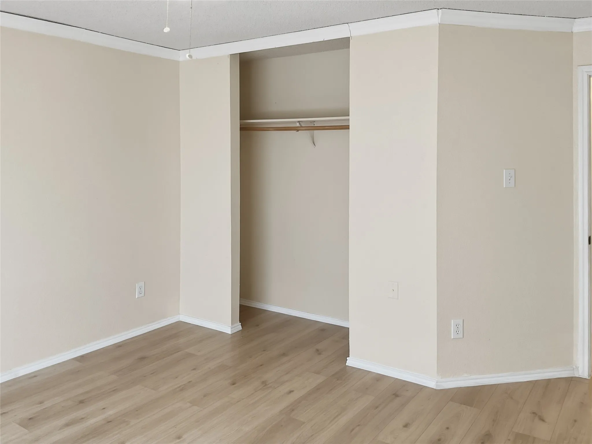 Wood-finish flooring, neutral wall color, and crown molding