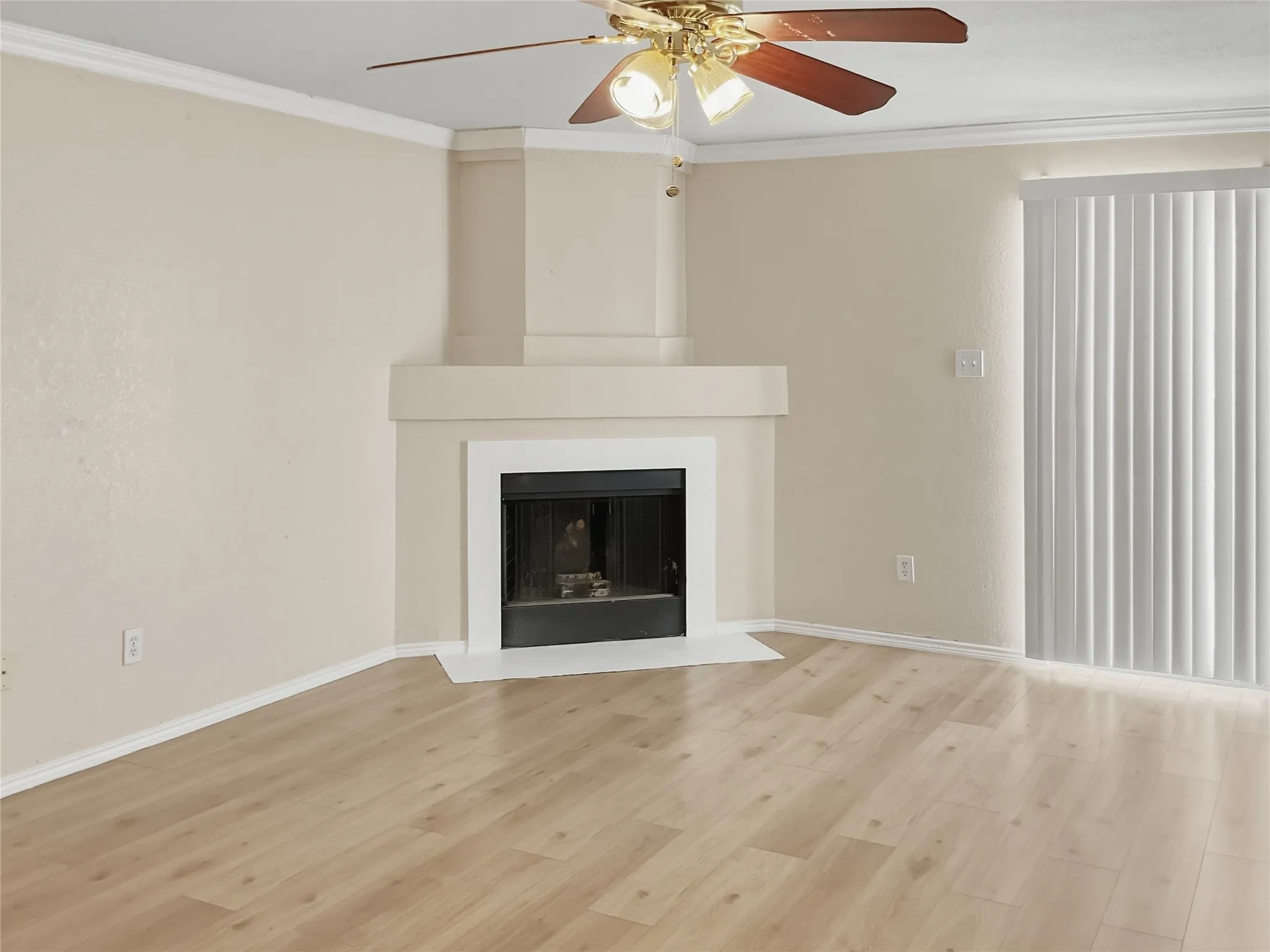 Fireplace with a white mantel, wood-finish flooring, ceiling fan with integrated lighting, and vertical blinds