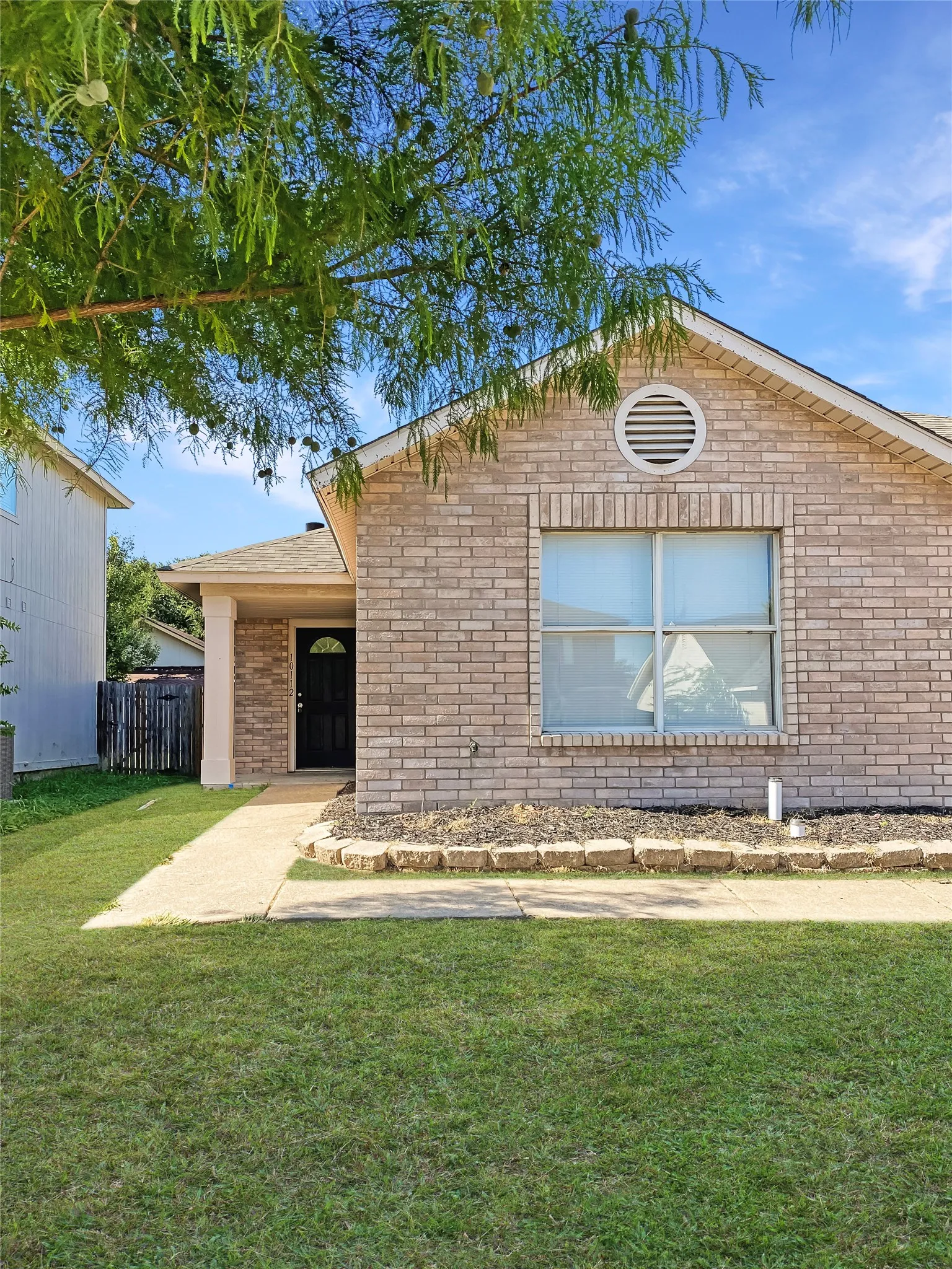 Brick facade home with a circular gable vent and a covered entryway