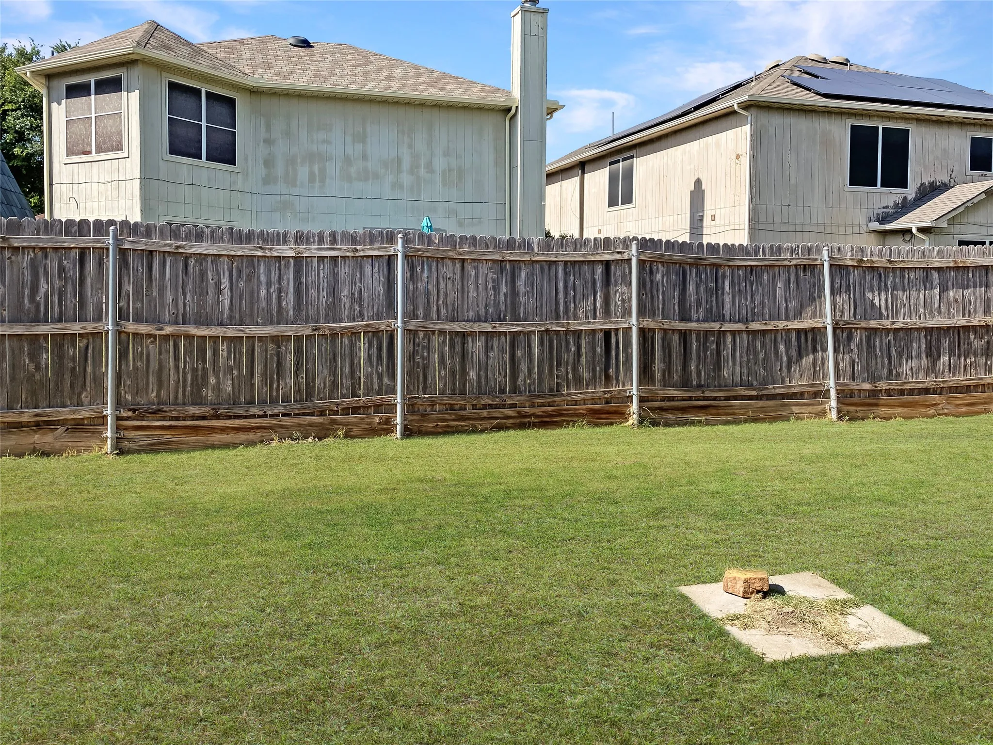 Expansive yard featuring a wood privacy fence and a concrete pad