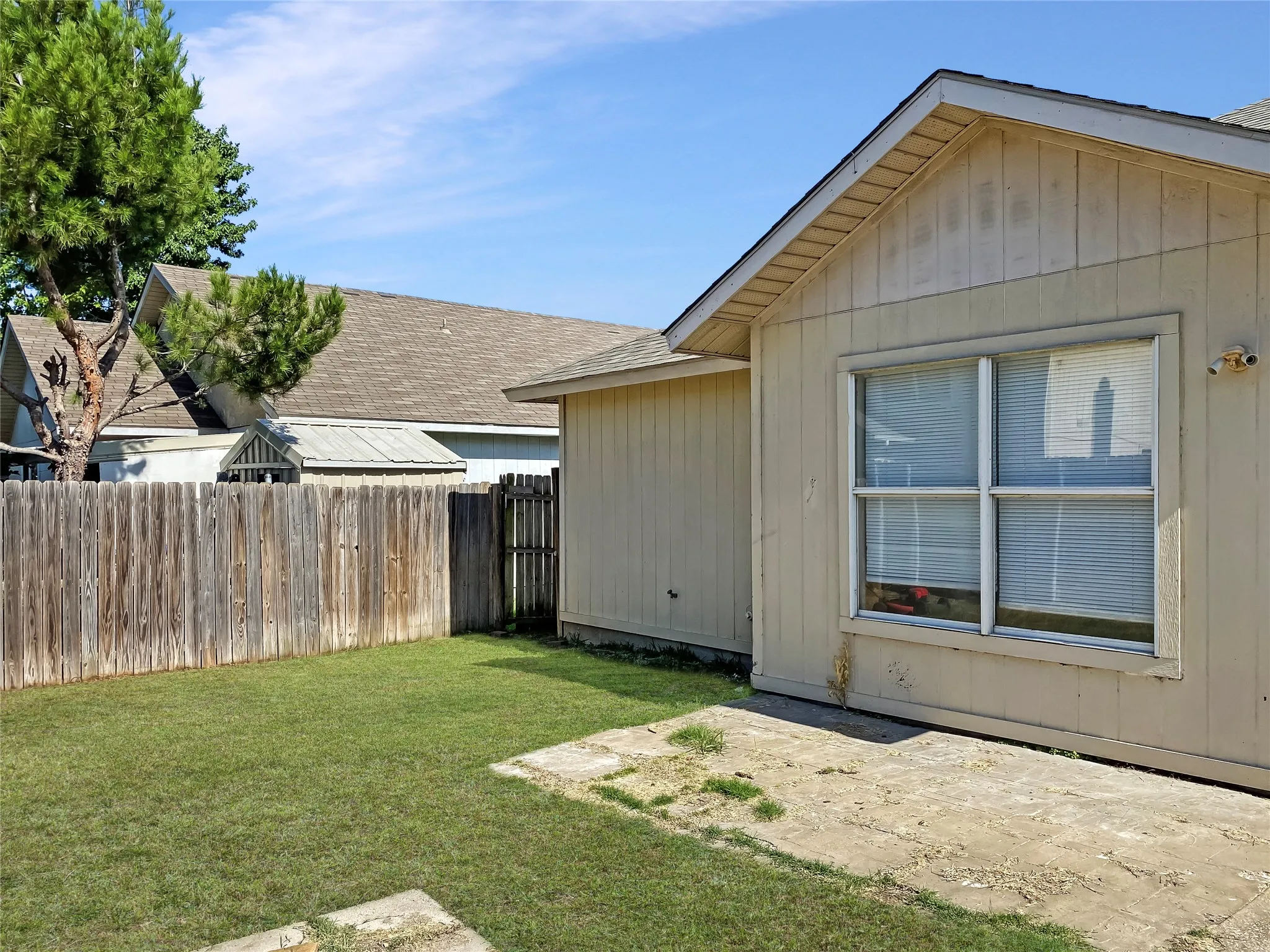 Spacious backyard with mature landscaping and manicured lawn, bordered by wooden fencing
