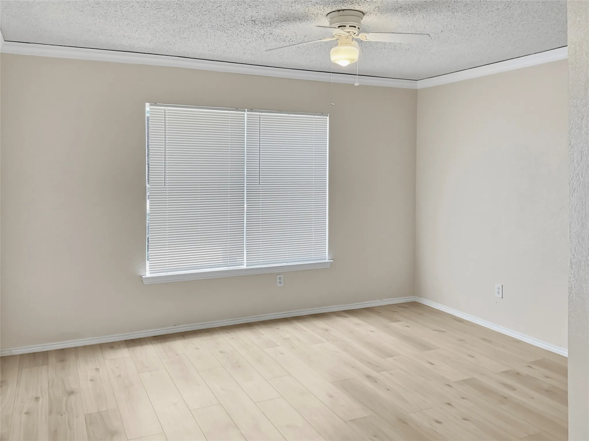 Bright and spacious bedroom featuring pristine wood-finish flooring, neutral wall finishes, horizontal blinds at the window, and a ceiling-mounted fan with integrated lighting fixture