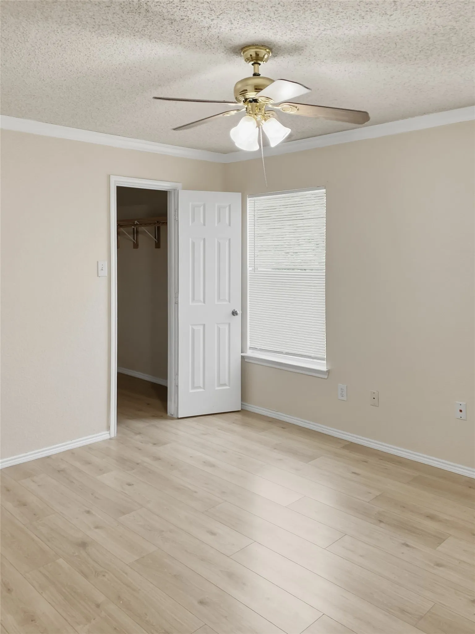 Wood-finish flooring, crown molding, and a ceiling fan with integrated lighting