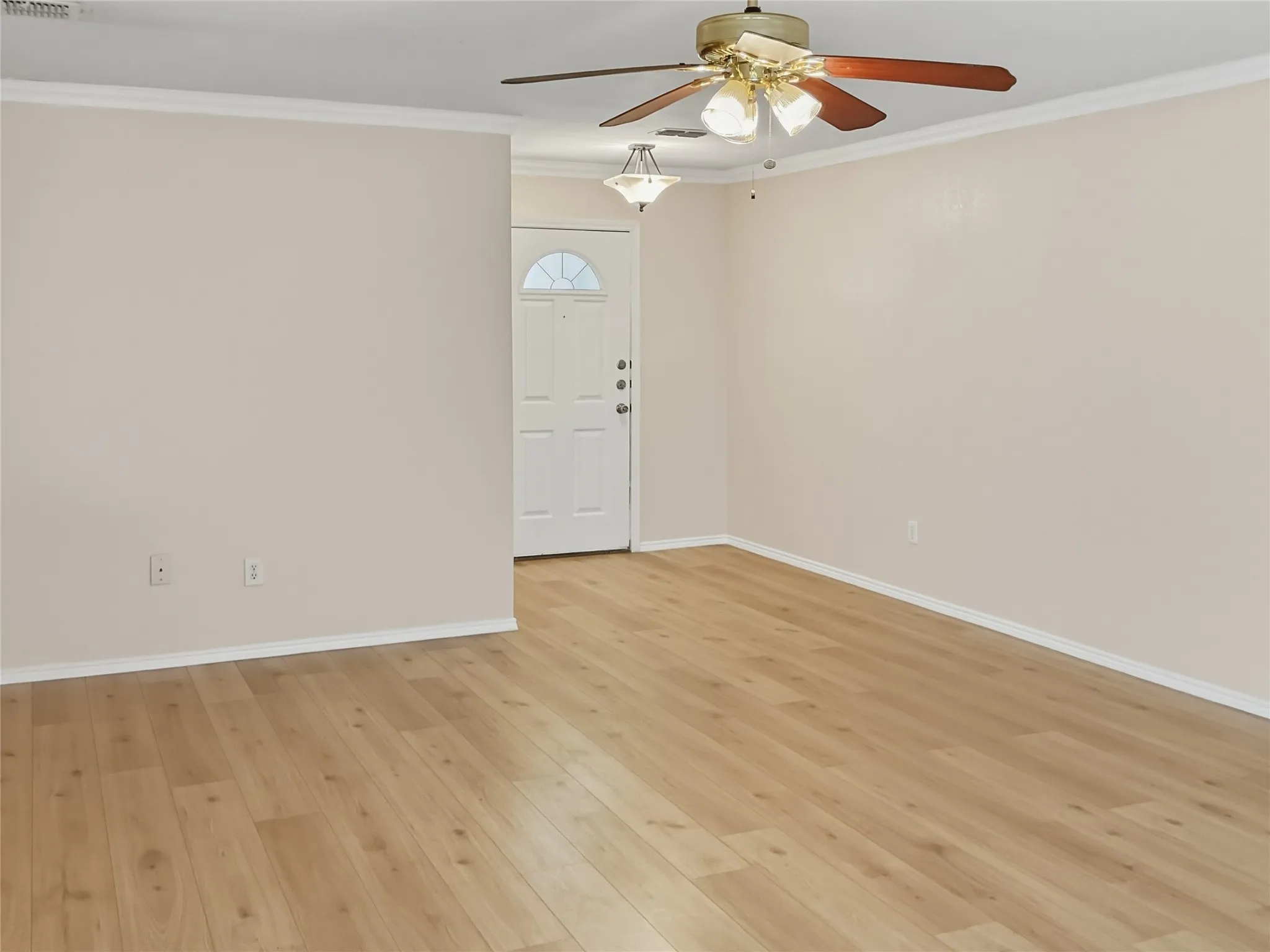 Wood-finish flooring, crown molding, ceiling fan with integrated lighting, recessed lighting fixture, and a paneled entry door with an arched window insert