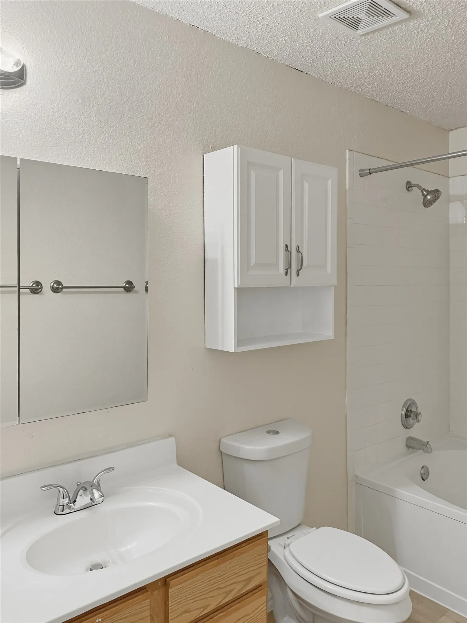 White vanity with a single basin sink, chrome faucet, and wood-finish cabinetry