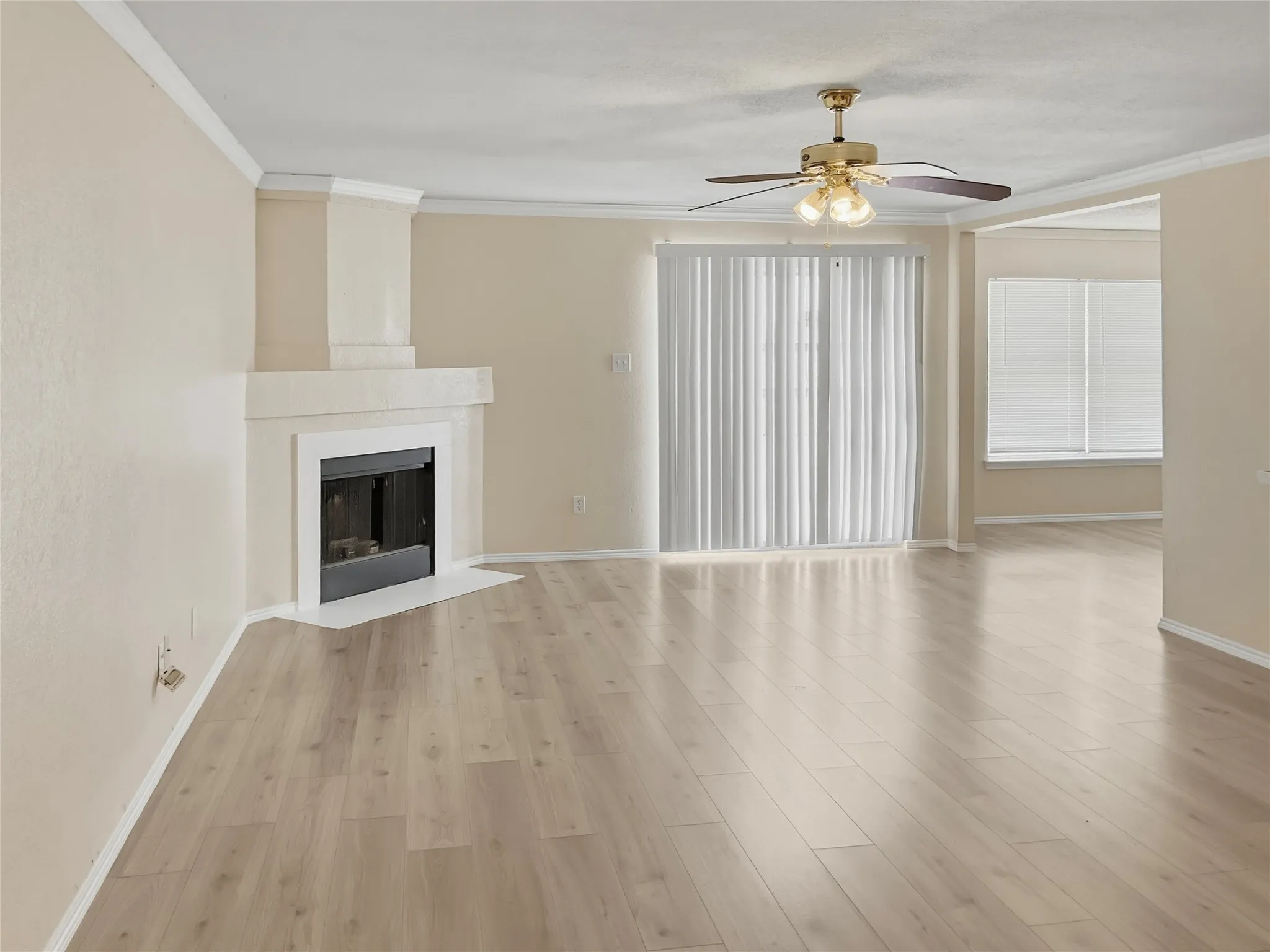 Contemporary fireplace with a hearth, wood-finish flooring, ceiling fan, and crown molding