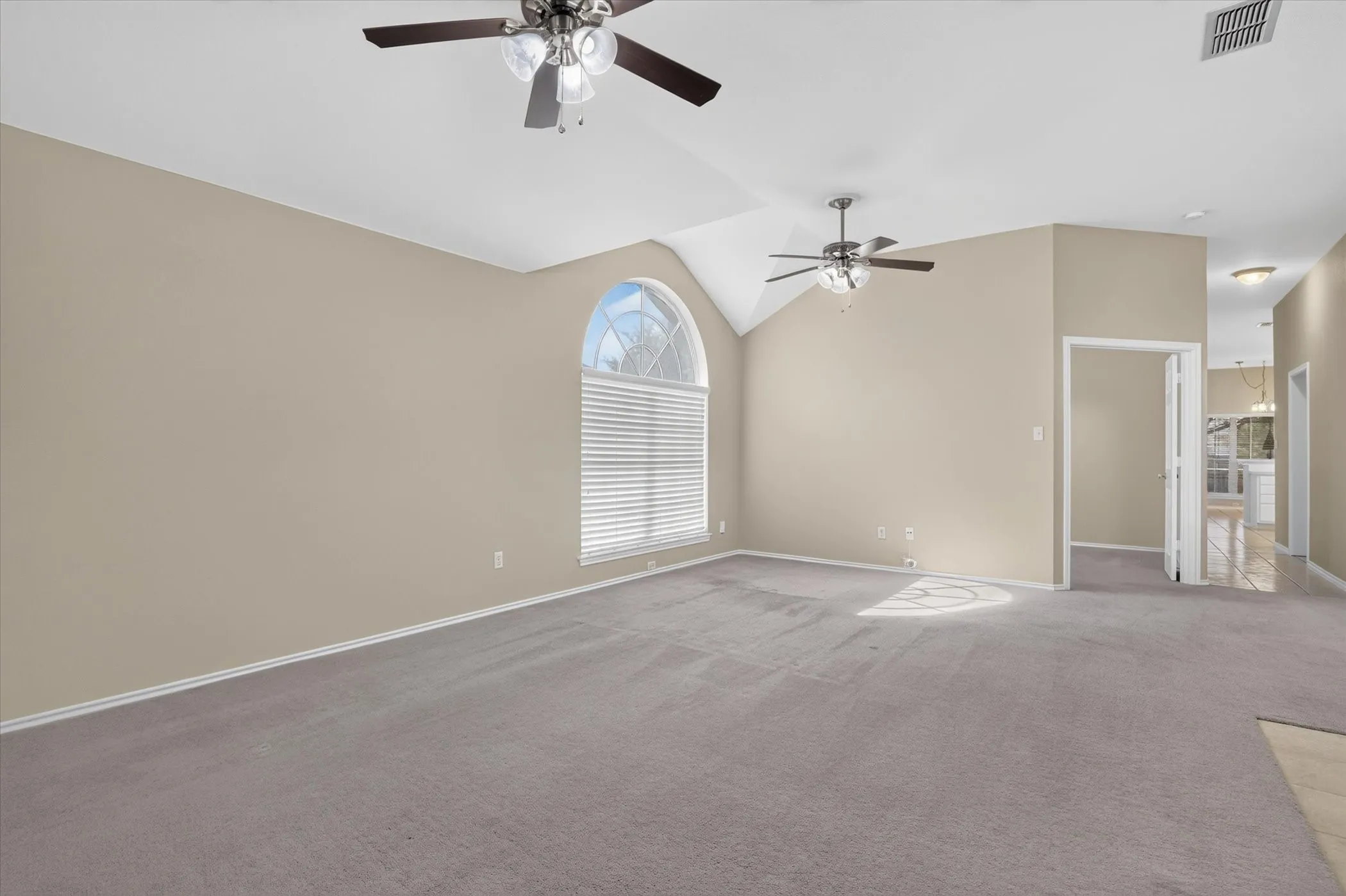 Vaulted ceilings with ceiling fans, arched window with horizontal blinds, neutral wall paint, and gray carpet flooring