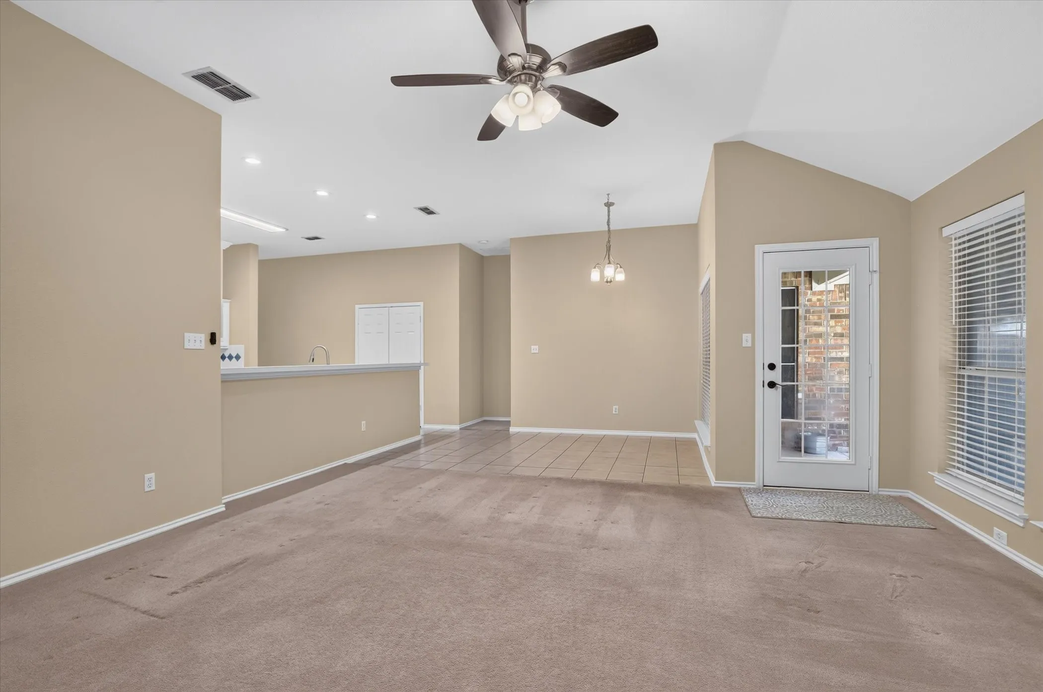 Vaulted ceiling with a ceiling fan, recessed lighting, and a glass-paneled door